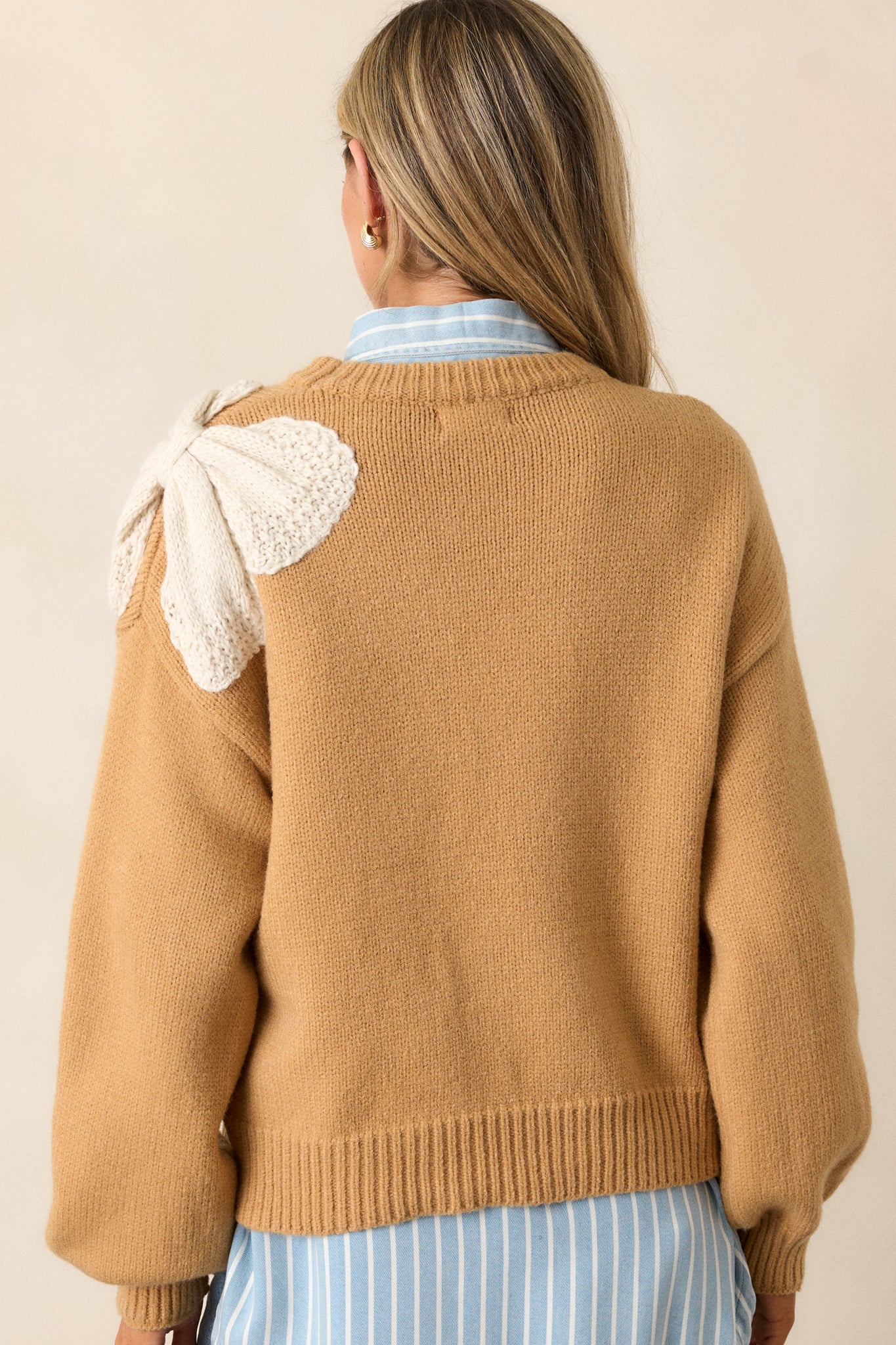 View of the back of the sweater, featuring the smooth honey-colored fabric and the continuous boxy fit.