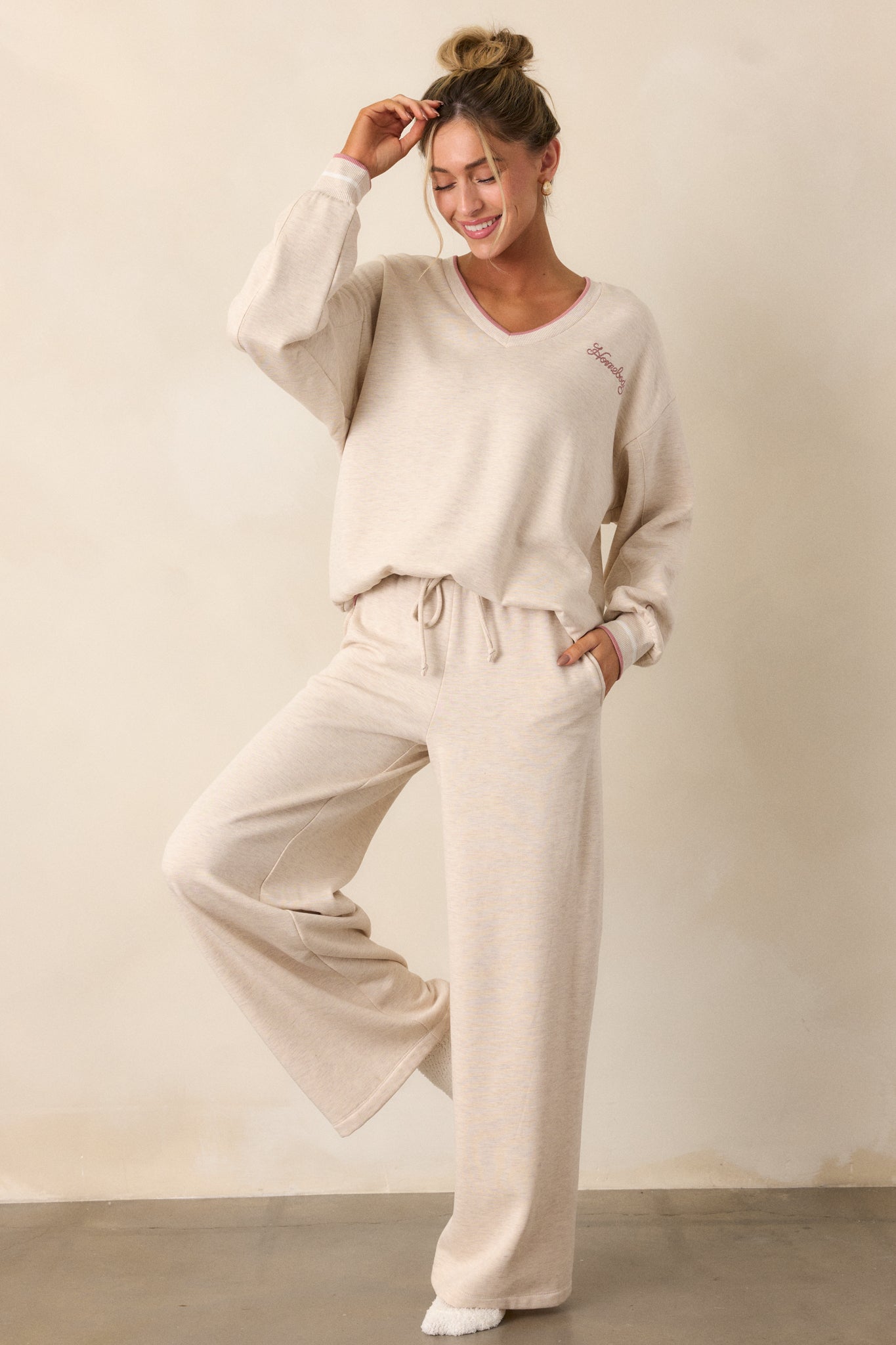 A full-body shot of the oatmeal pants, highlighting the high-waisted design with an elastic waistband and self-tie drawstring. The wide leg fit is visible, along with the soft fleece material and functional hip pockets.