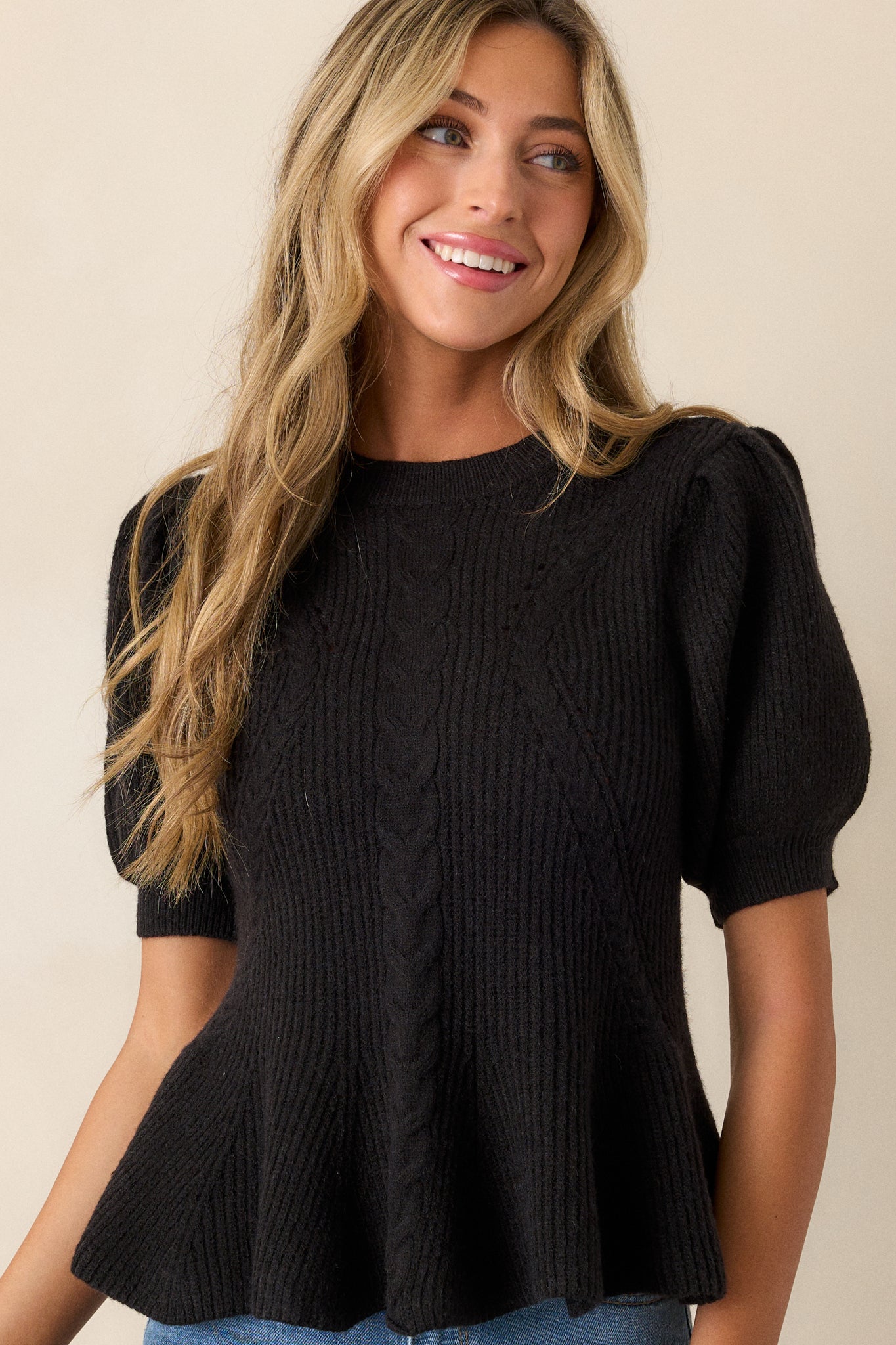 A cropped close-up of the puff sleeves on the black sweater, showing the ribbed cuffs and subtle texture.