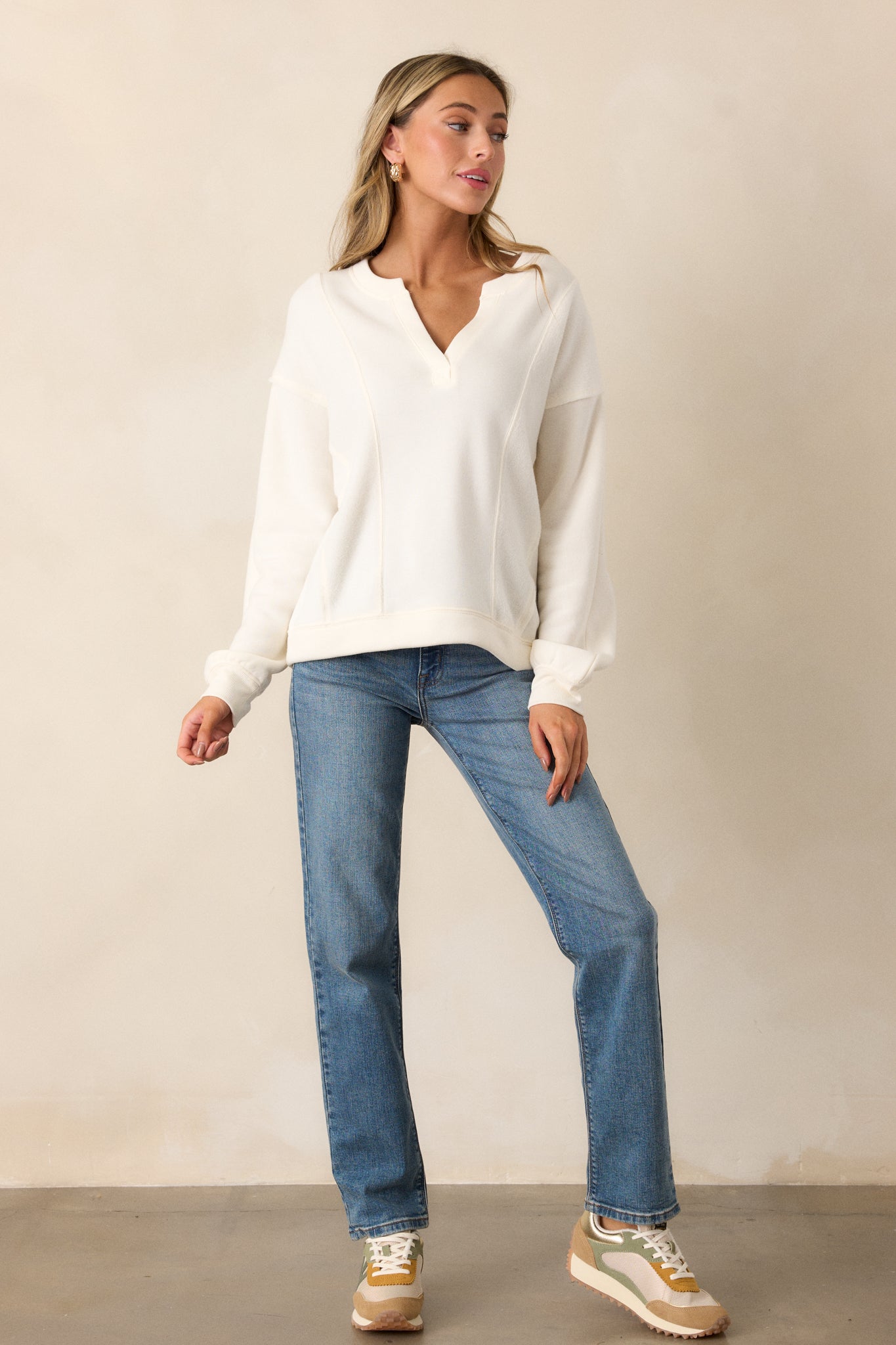 Full-length shot of the ivory sweatshirt showing the split neckline, relaxed silhouette, and subtle reverse paneling details.