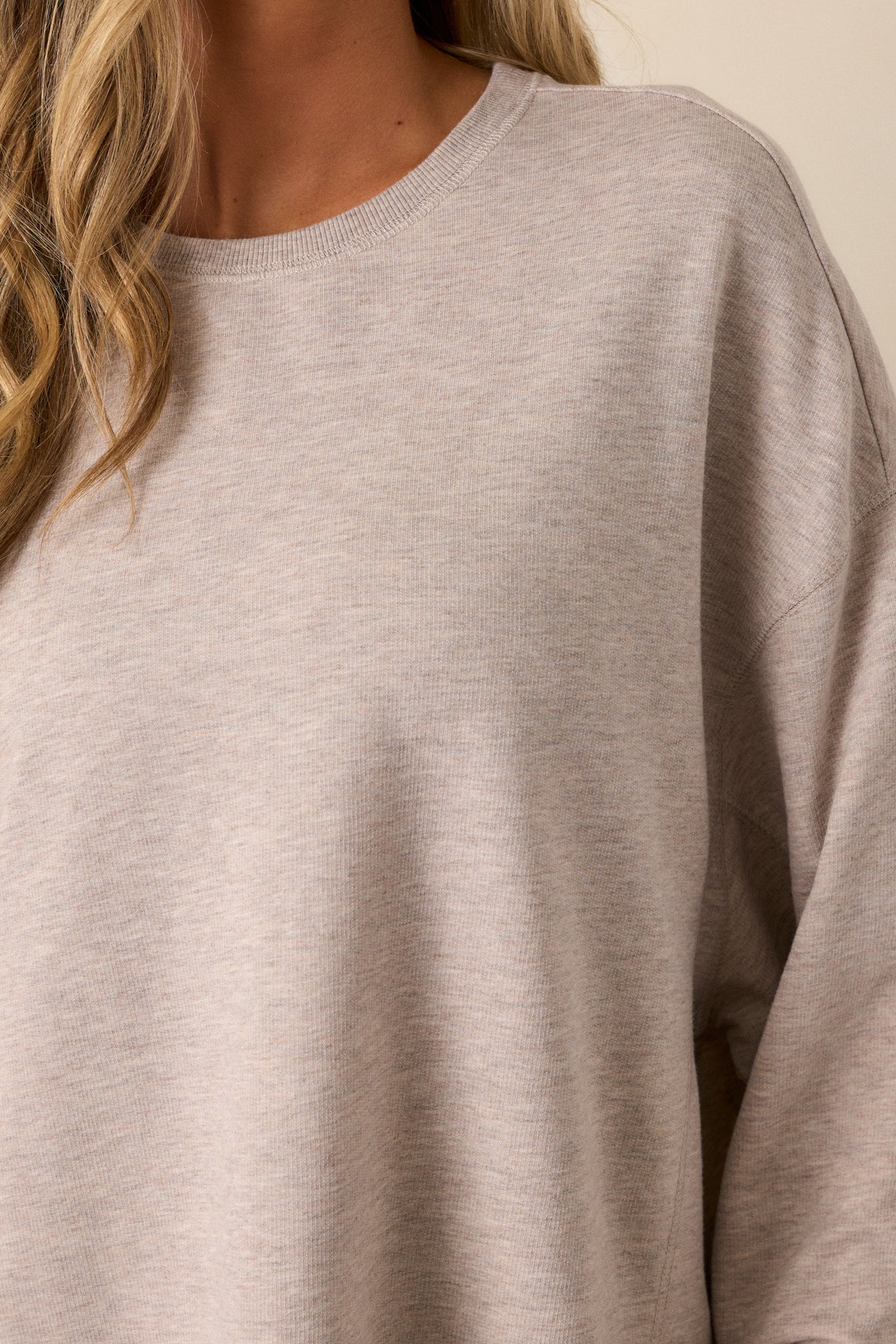 Close-up of the taupe top’s fabric texture, emphasizing the ribbed cuffs and split hemline details.