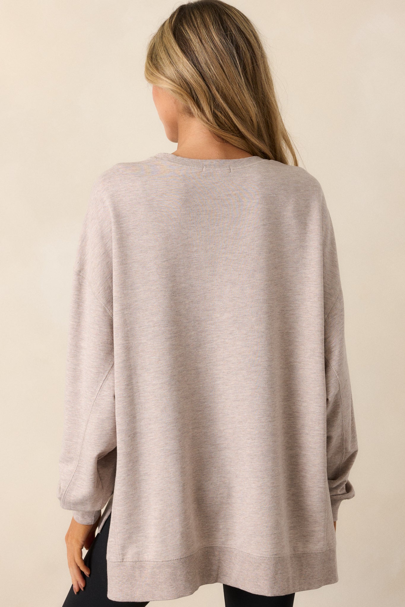 Back view of the taupe top, showing the high-low split hemline, oversized fit, and drop shoulders from the rear perspective.