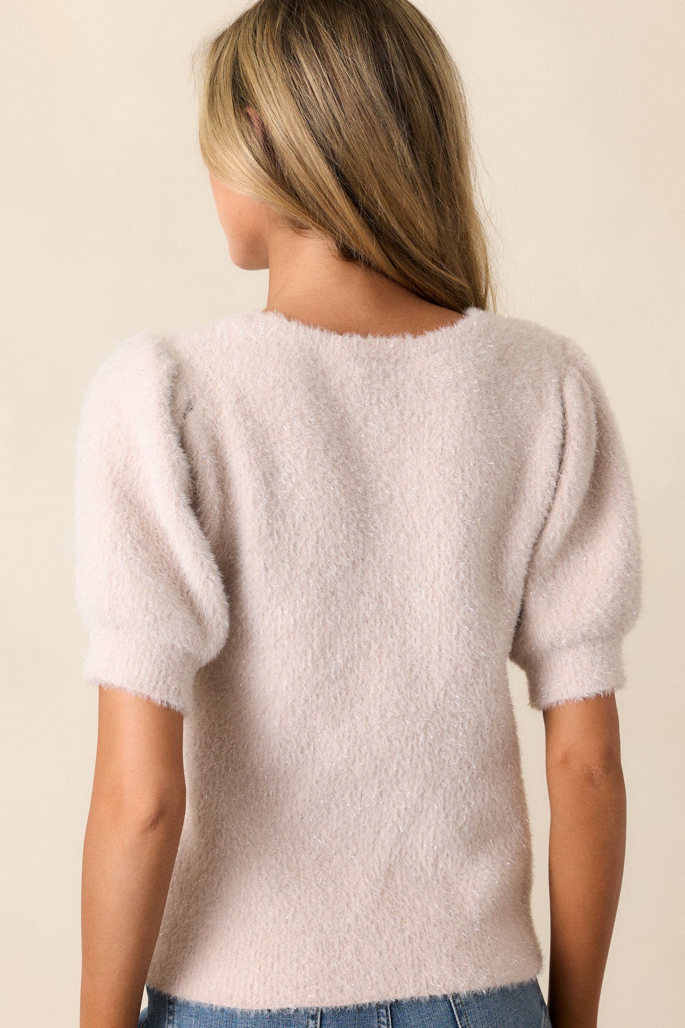 View of the back of the sweater, featuring the continuous fuzzy knit material and ribbed hem, with metallic tinsel adding subtle sparkle.