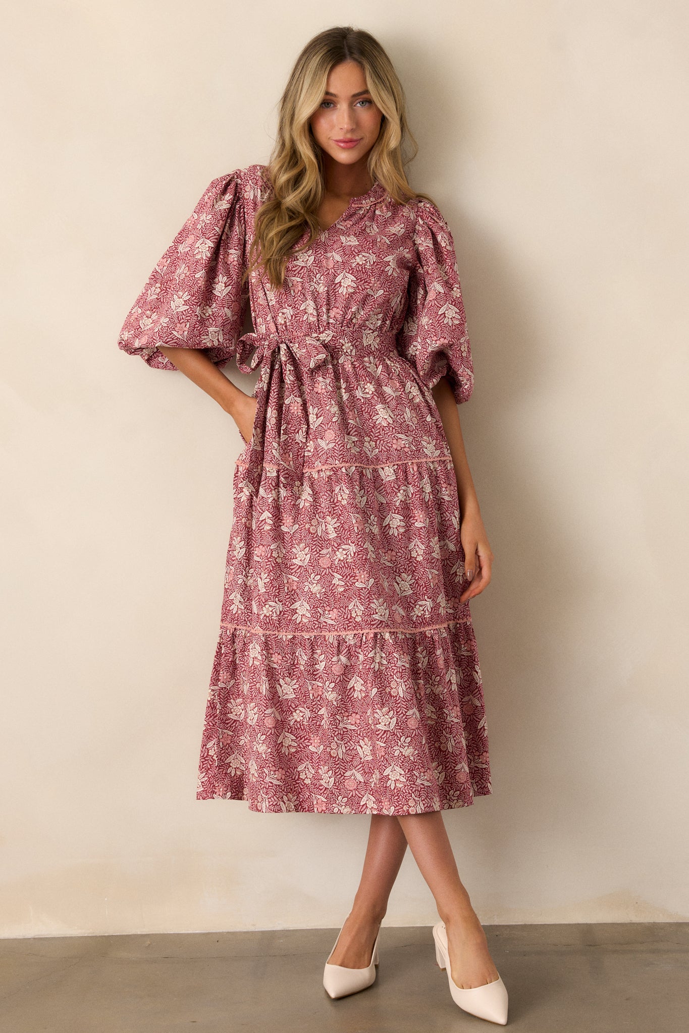 Full view of the dark sangria dress featuring a split v-neckline, short puff sleeves with elastic cuffs, and a vibrant floral pattern throughout.
