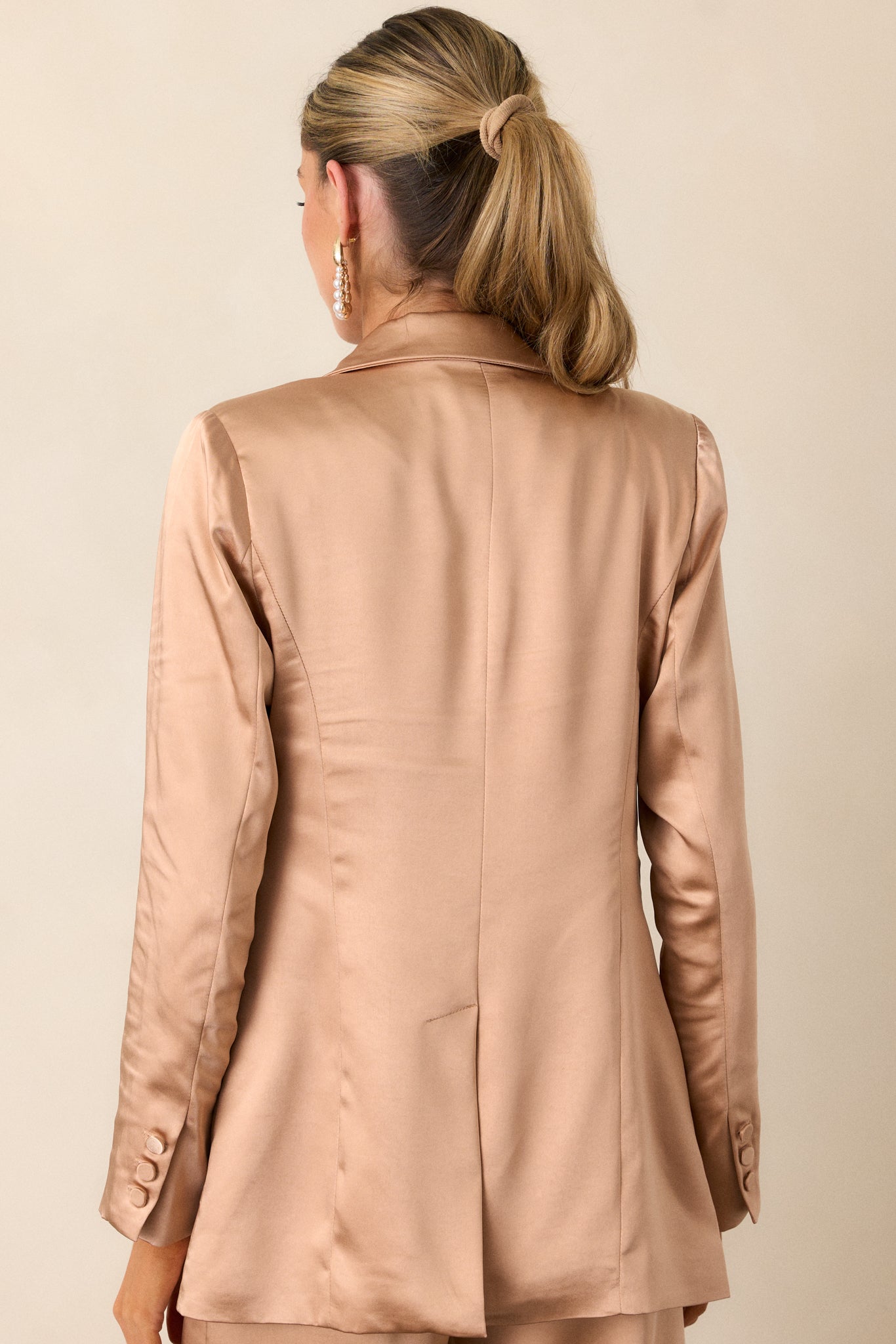 View of the back of the blazer, featuring the vent back design and the smooth flow of the light copper fabric for a polished look.