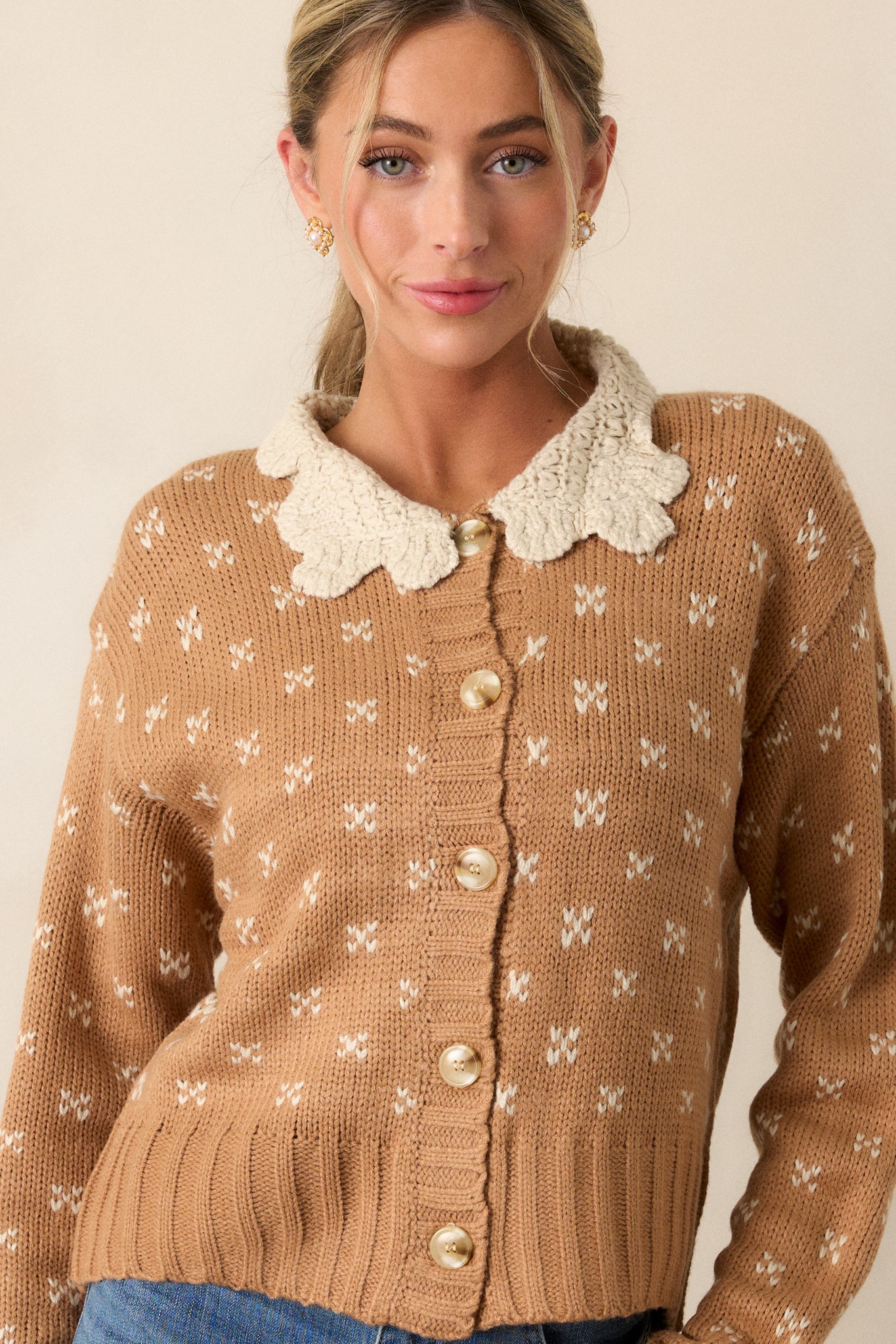 Fully buttoned up view of a honey cardigan featuring an ivory crochet peter pan collared neckline, functional button front, ditsy heart cluster print, and long sleeves with ivory crochet wrist cuffs.