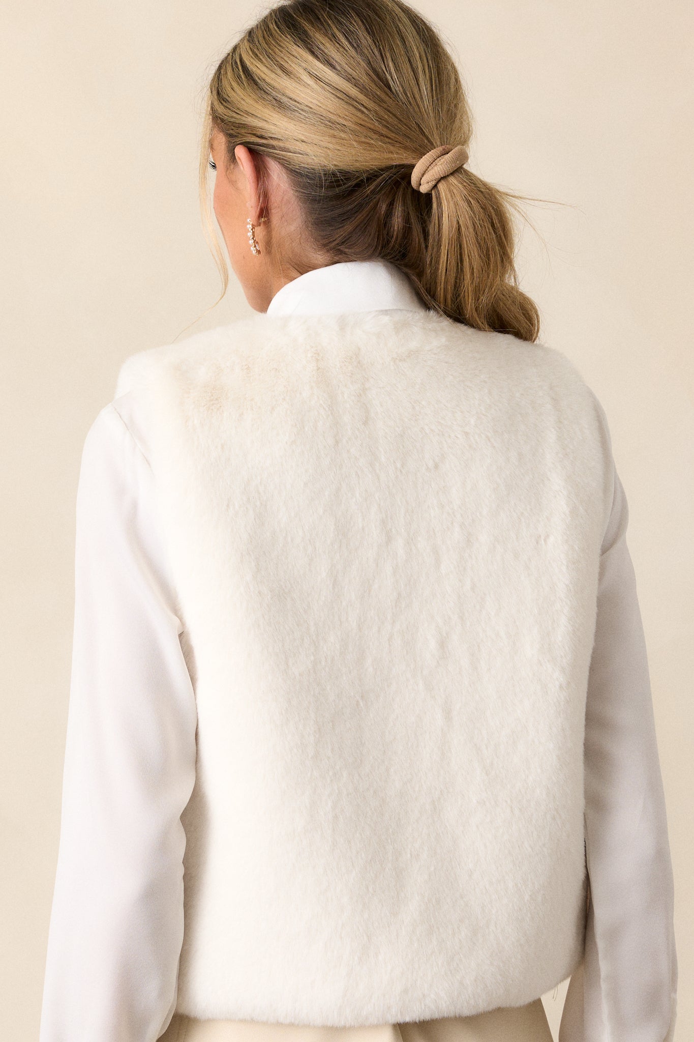 Back view of an off white vest features an open vest design, faux fur fabric, and sleeveless cut.