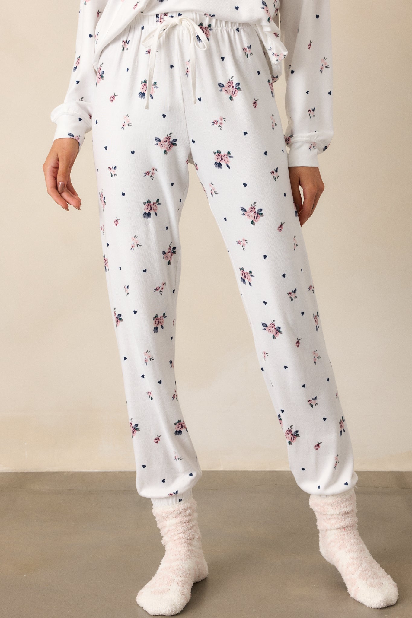 A cropped shot focusing on the elastic self-tie waistband and the relaxed fit of the ivory joggers. The rosebud pattern is visible, and the elastic ankle cuffs provide a snug finish to the pants.