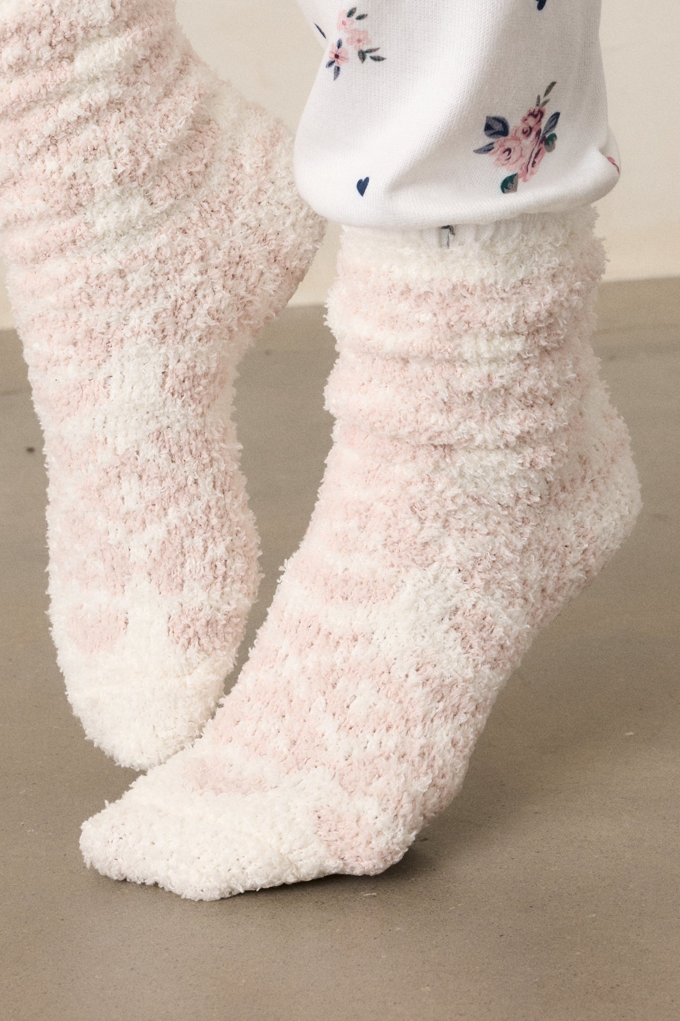 A detailed shot of the grey socks, zooming in on the fuzzy texture and the pink hearts and decorative shapes woven into the fabric, showing the softness and unique design of the socks.