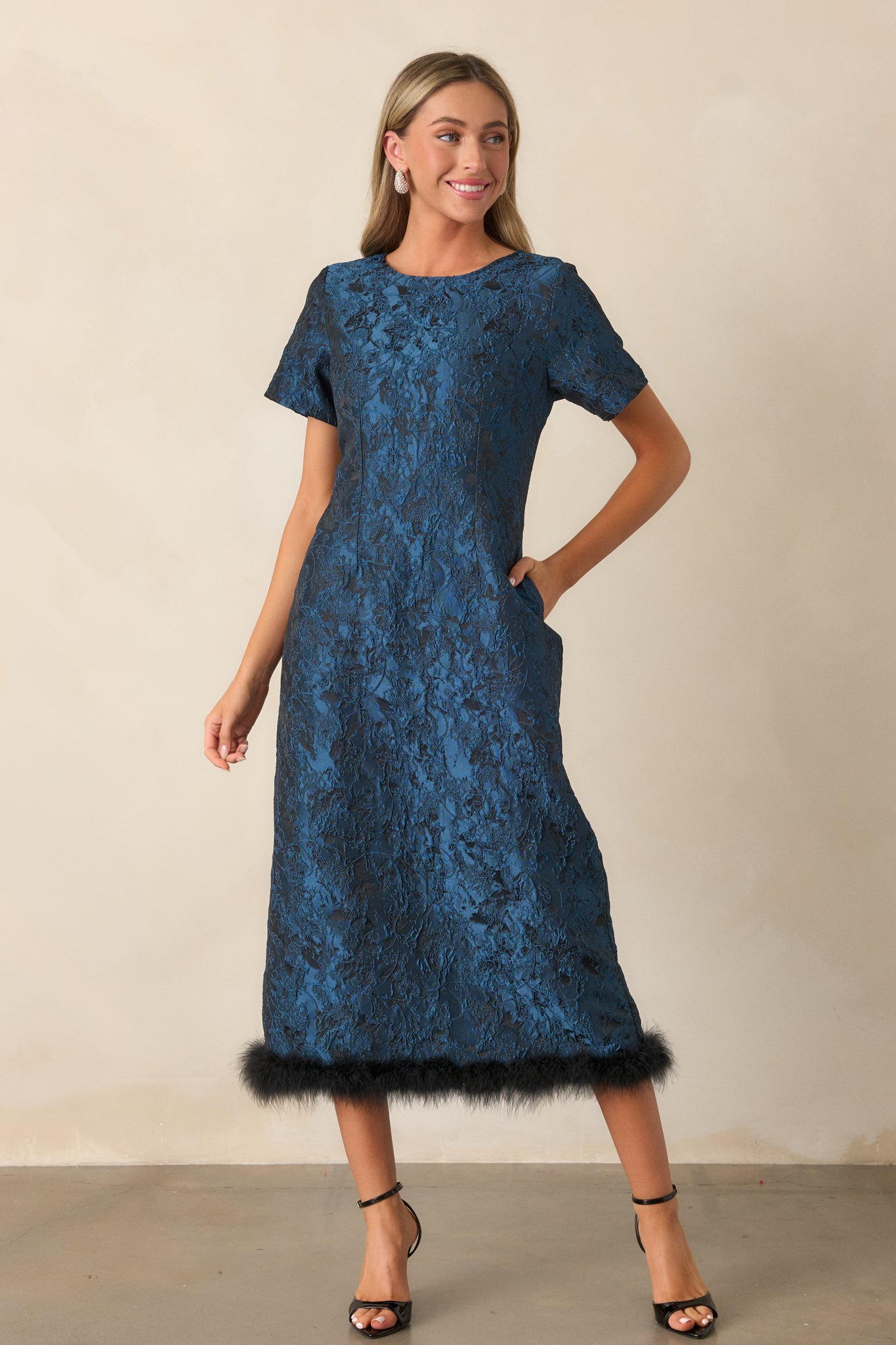 A slightly angled view of the dress, highlighting the fitted silhouette, round neckline, and the stylish faux fur trim at the bottom.