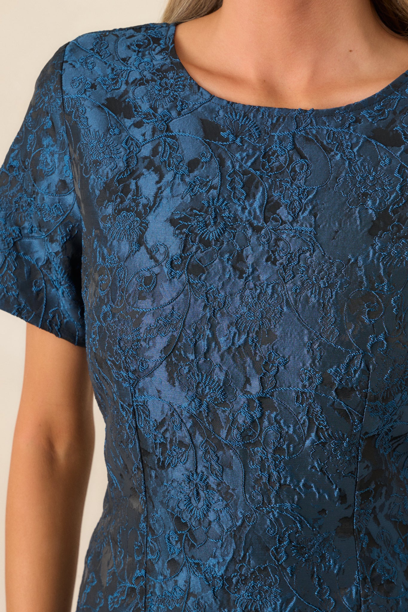 Close-up of the round neckline and intricate designs, showcasing the texture of the fabric and the short sleeves.