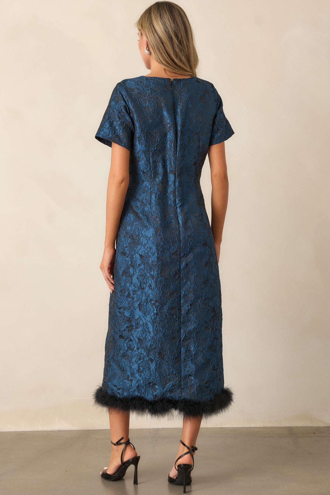 Back view of the dark teal midi dress, focusing on the discreet back zipper and the structured design, with the faux fur hem visible at the bottom.