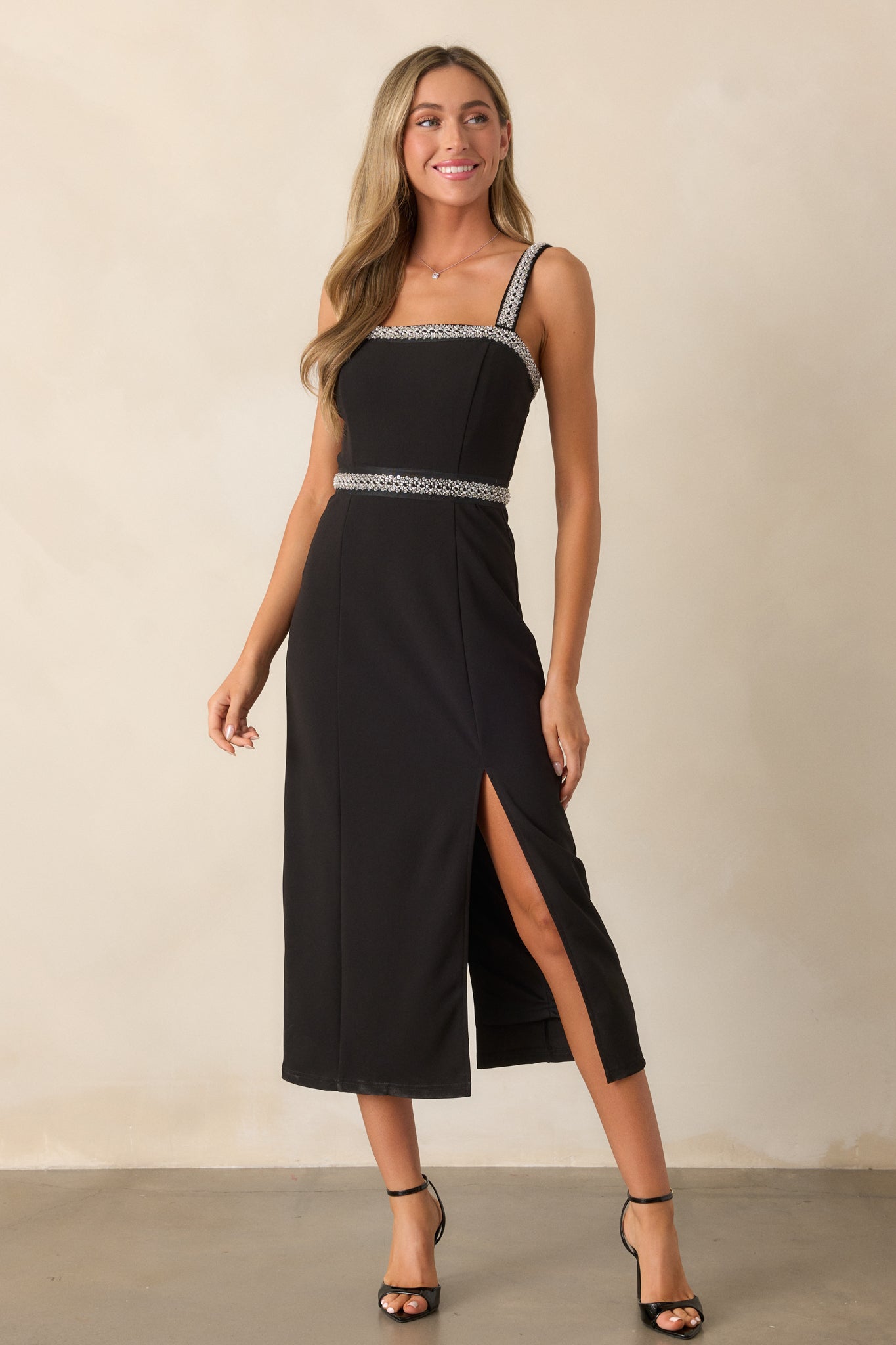 Slightly angled front view of the black midi dress, focusing on the beaded shoulder straps and the graceful design of the leg slit.