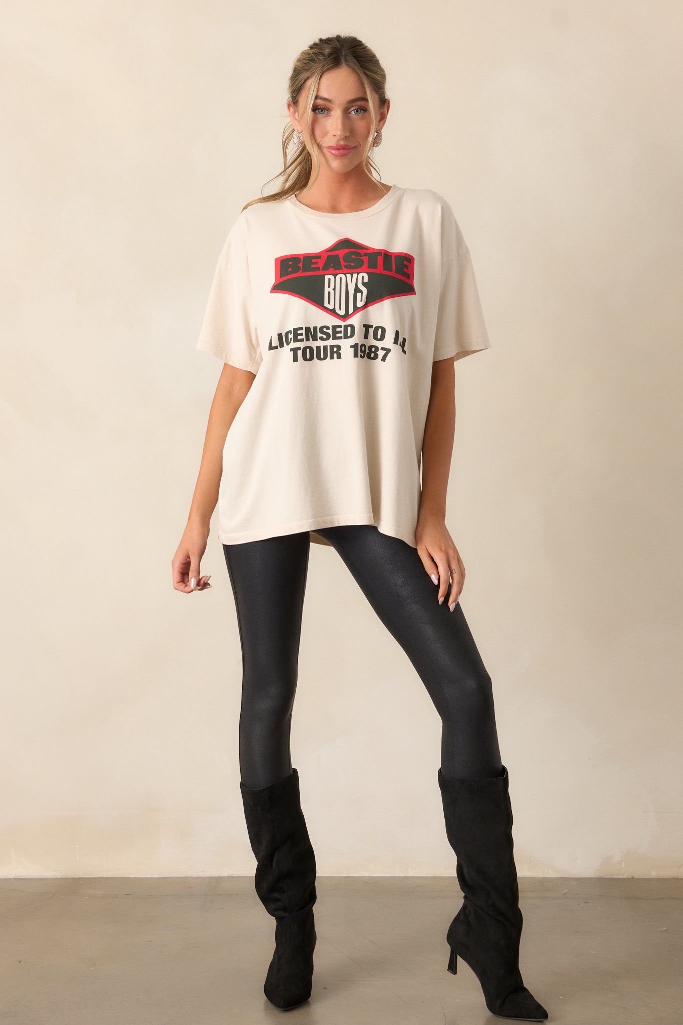 An ivory tee with a round neckline, short sleeves, and a bold 'Beastie Boys 1987' graphic displayed prominently on the front.