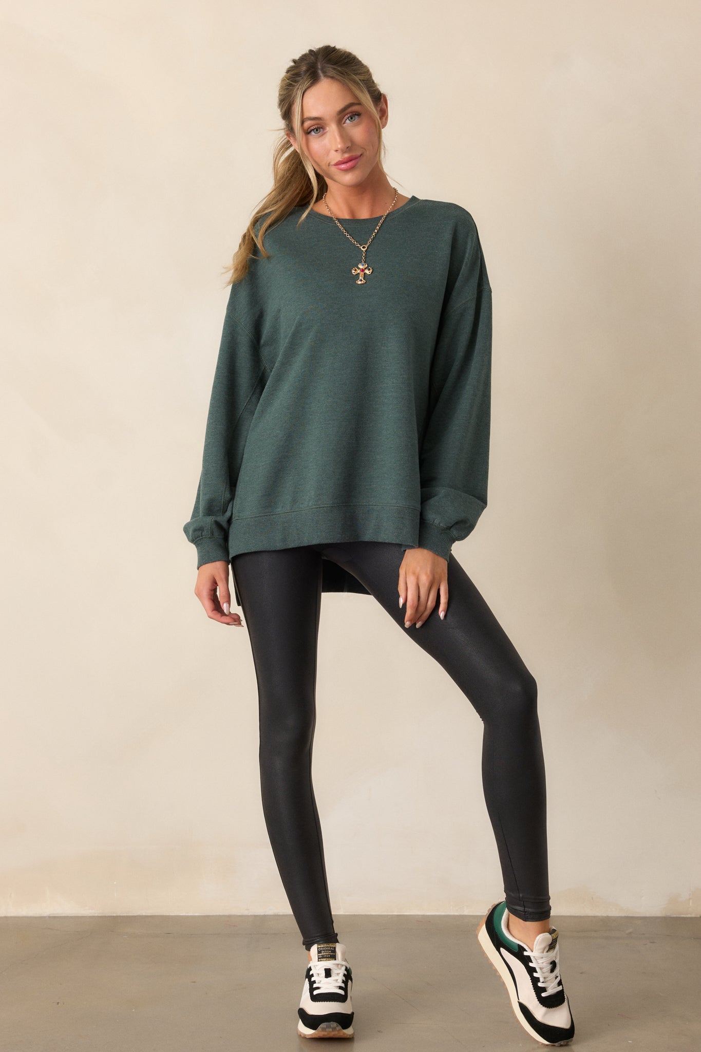 Full body view of a forest green top with a crew neckline, oversized fit, and split bottom hem. The long sleeves and soft french terry fabric are visible.