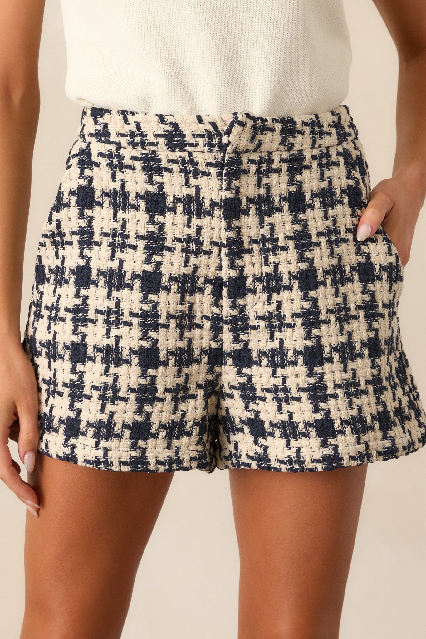 A close-up view of one of the functional hip pockets on the navy shorts, emphasizing the houndstooth design and the stitching details.