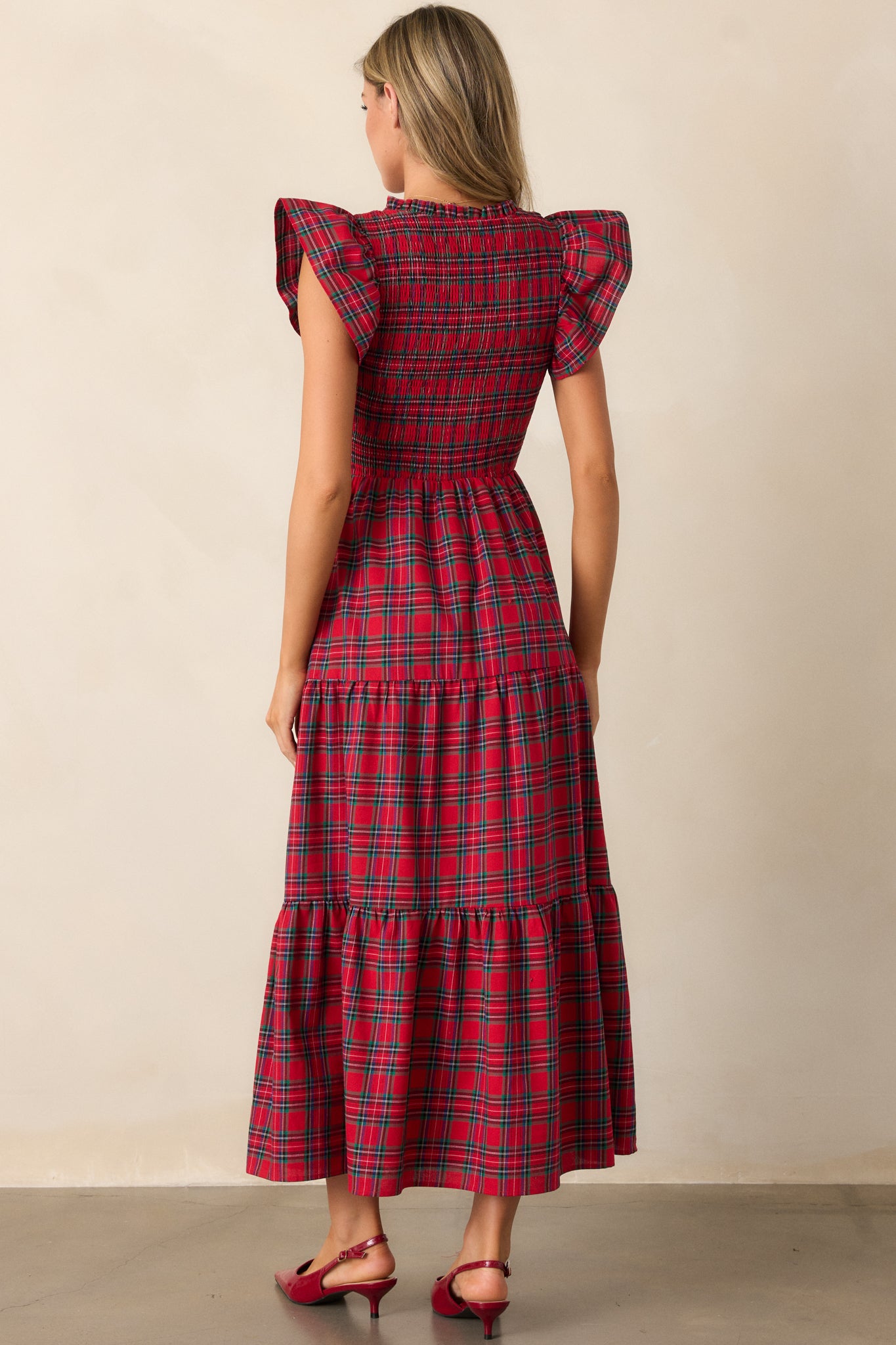 Back view of the red dress, highlighting the continuation of the plaid pattern and the flowy tiers of the skirt.