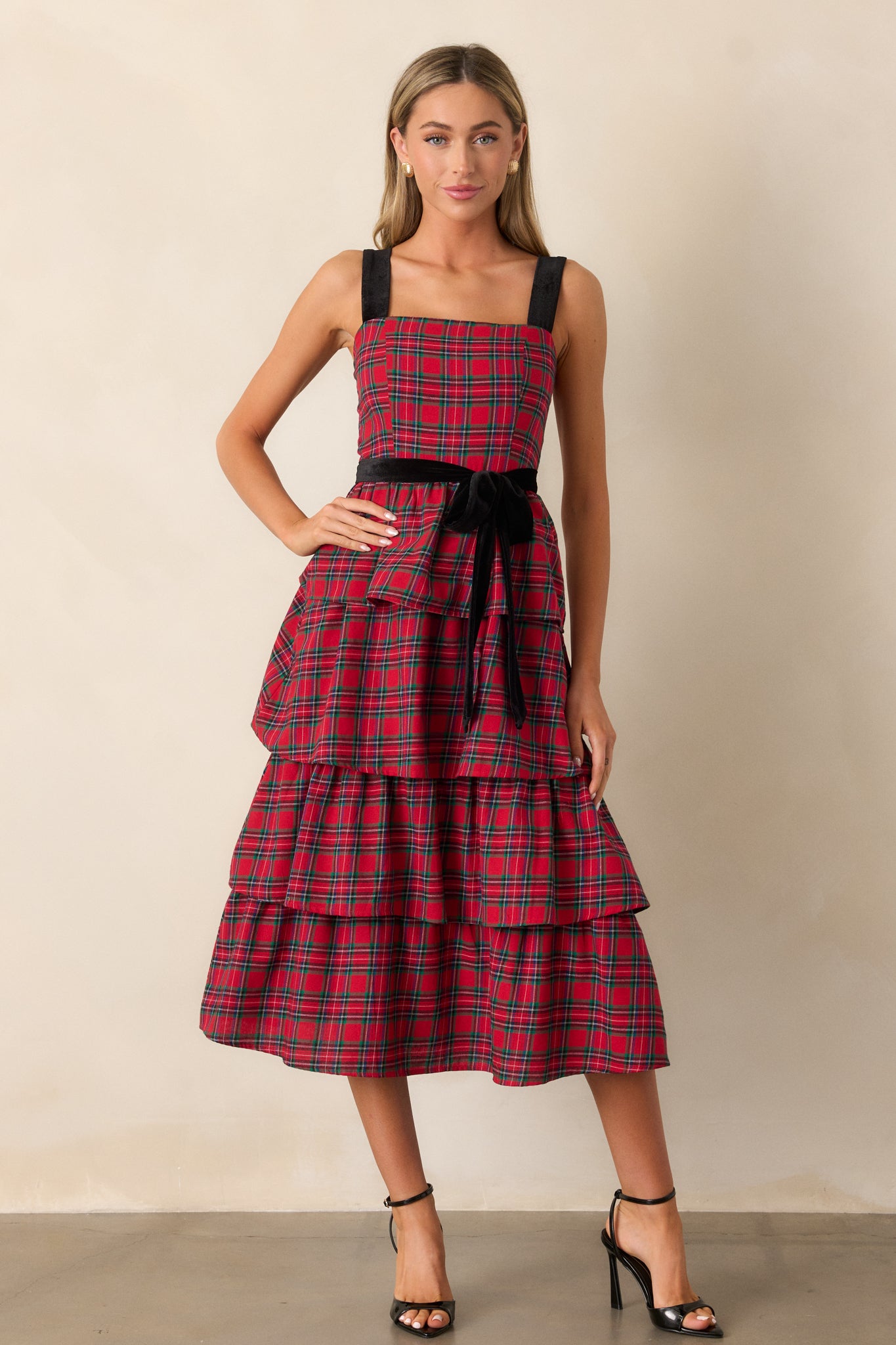 Front view of the red dress, featuring a square neckline, plaid print, tiered skirt, and velvet shoulder straps, creating a classic yet stylish look.