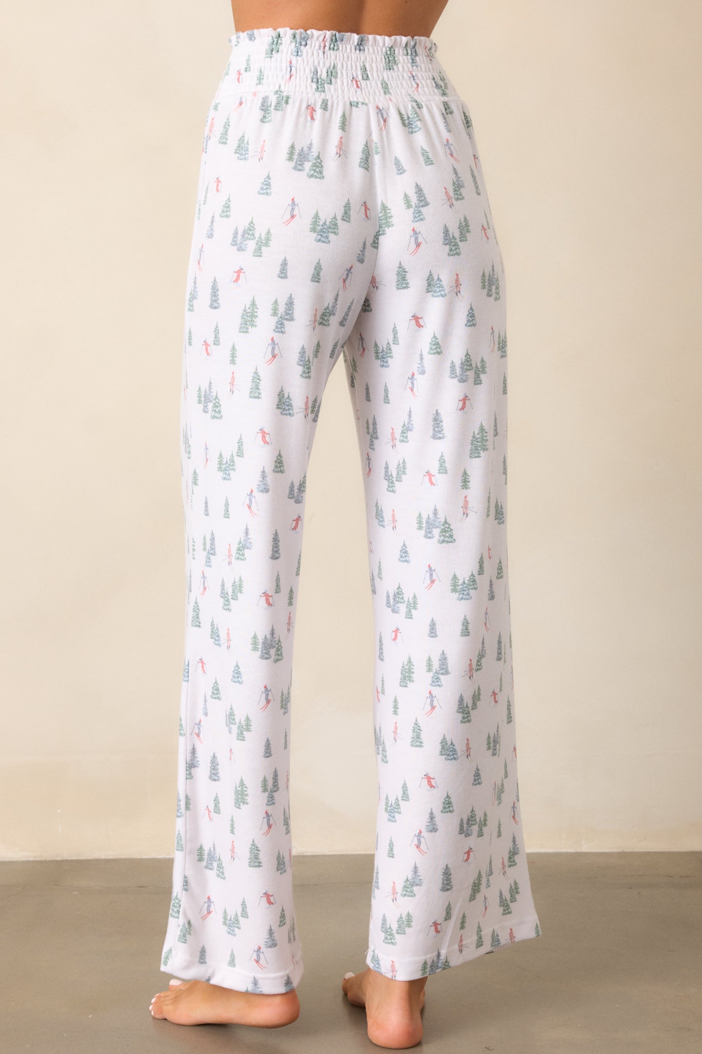 A view from the back of the ivory pants, showing the full length and relaxed fit, with a focus on the smooth waistband and the alpine skier print extending down the legs.