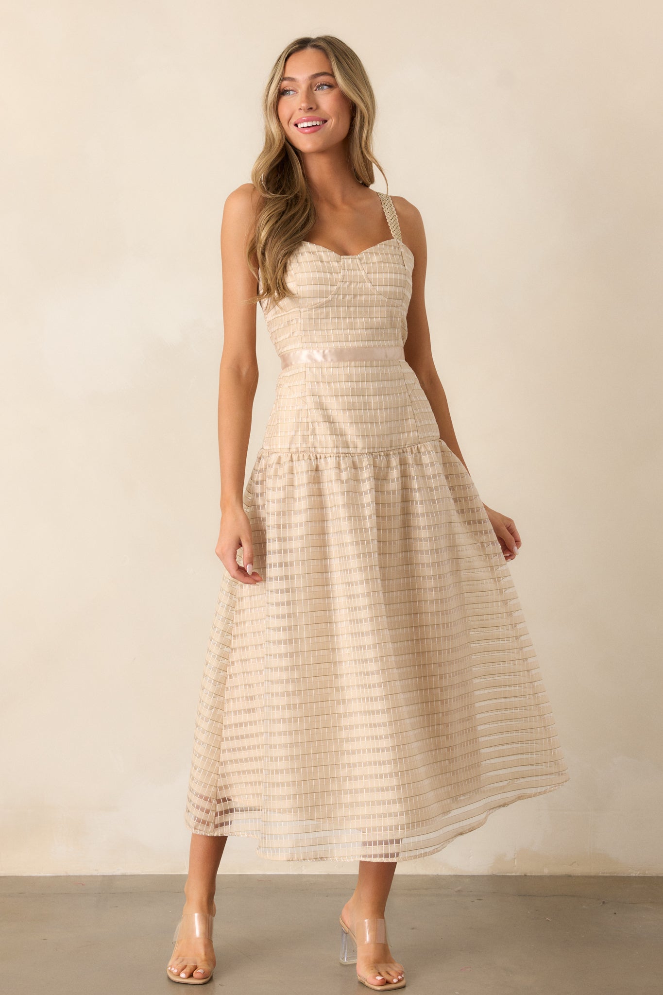 Full body view of the tan dress with adjustable embroidered straps, emphasizing the embroidered design across the fabric. The drop waist and ribbon waist detailing create a flattering fit, while the fluffy skirt adds texture and movement to the look.