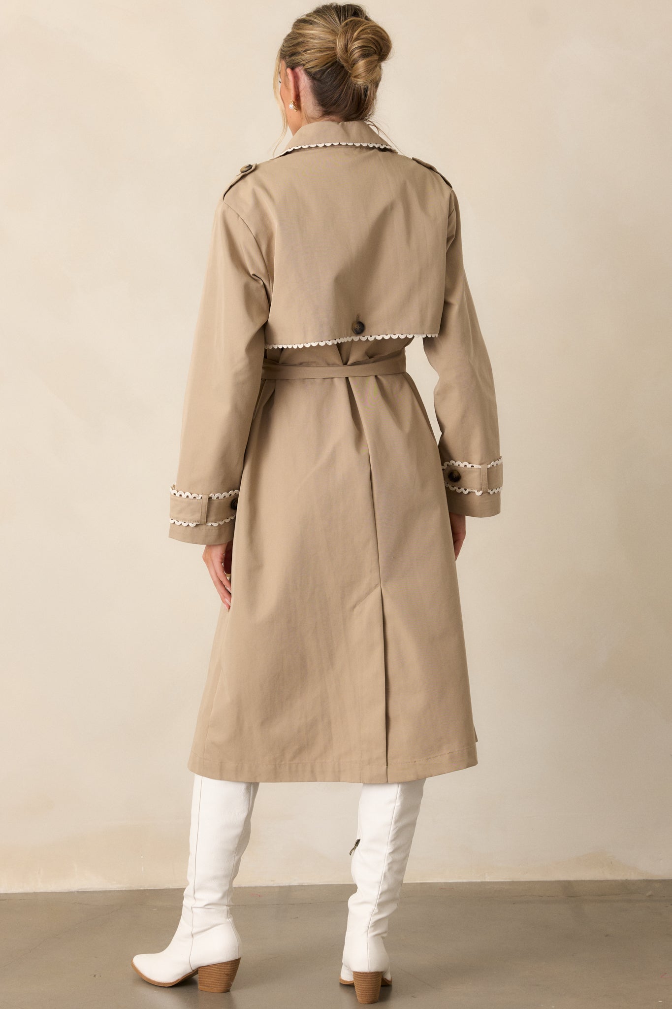 The back of the taupe trench coat, displaying the clean lines and understated elegance of the design.