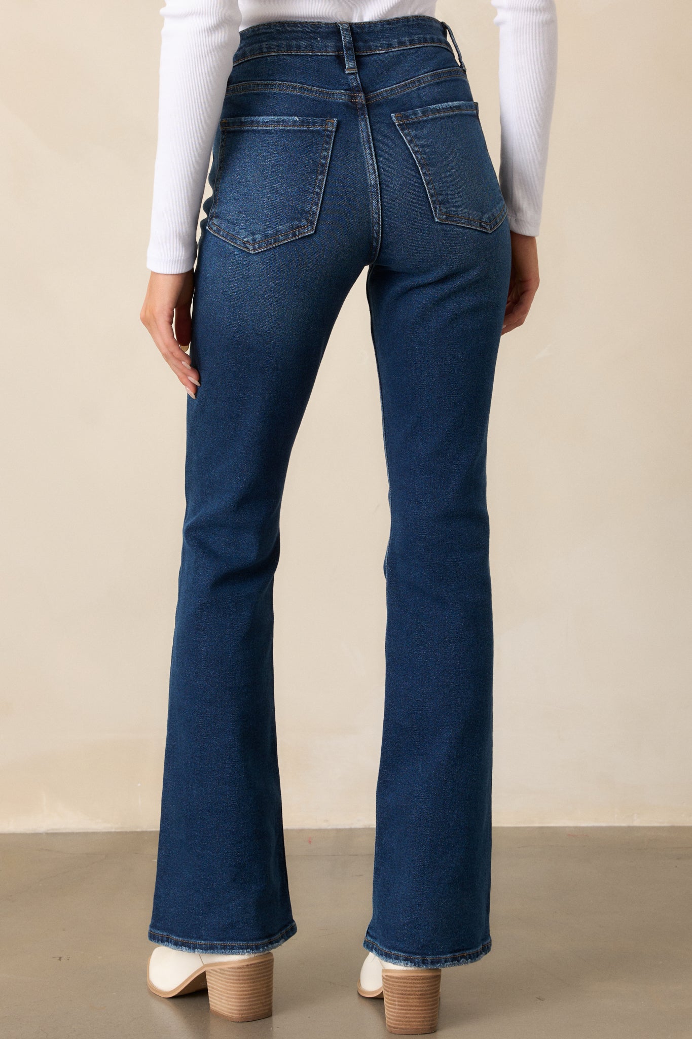 A back view of the high-waisted jeans showcasing the functional back pockets, belt loops, and flared style from behind.