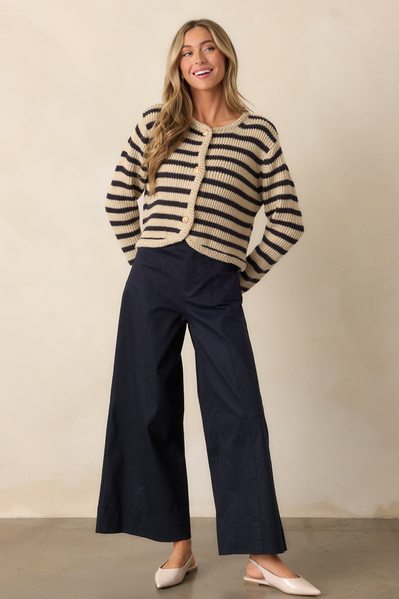 A full-body view of navy pants featuring a high-waisted design with a button and zipper closure. The pants are styled with a wide leg, and functional rectangular hip pockets are visible on either side, giving a relaxed yet structured silhouette.