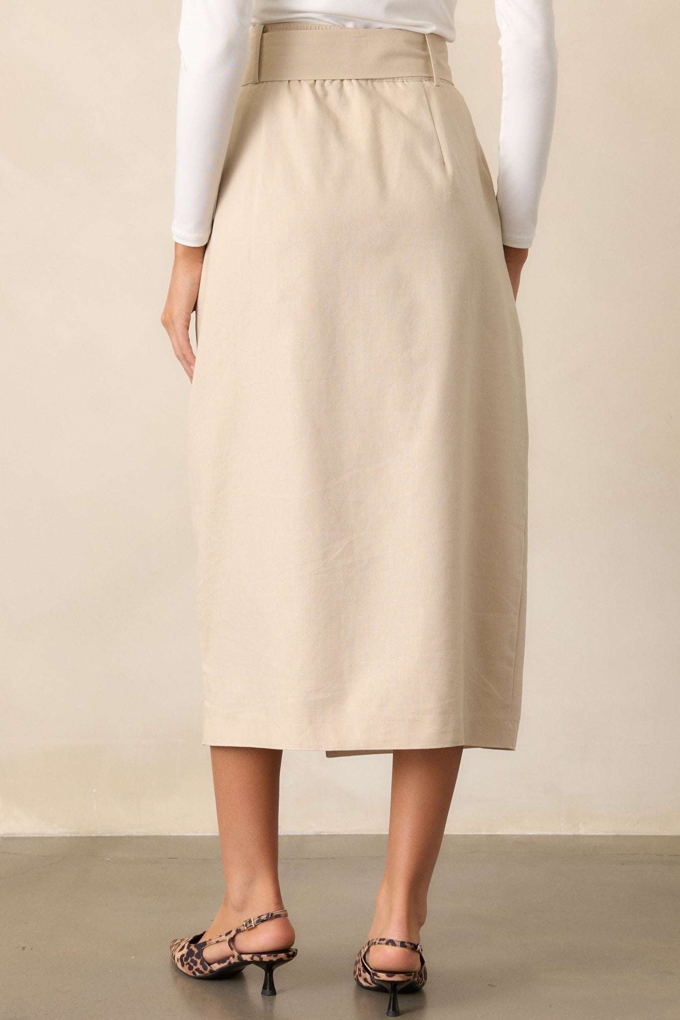 Back view of the beige maxi skirt showing the high-waisted design with an elastic insert and a smooth finish. The flowy fabric and long length are visible from behind.