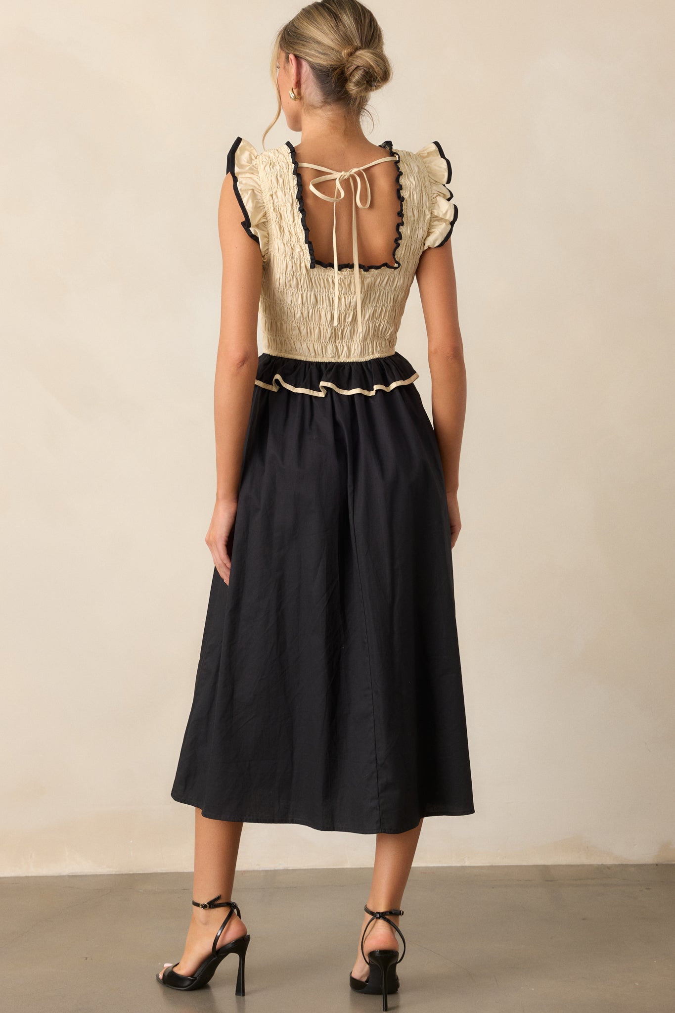 A back view of the dress, highlighting the tie at the bust for adjustment and the continuation of the alternating ivory and black design down the back.