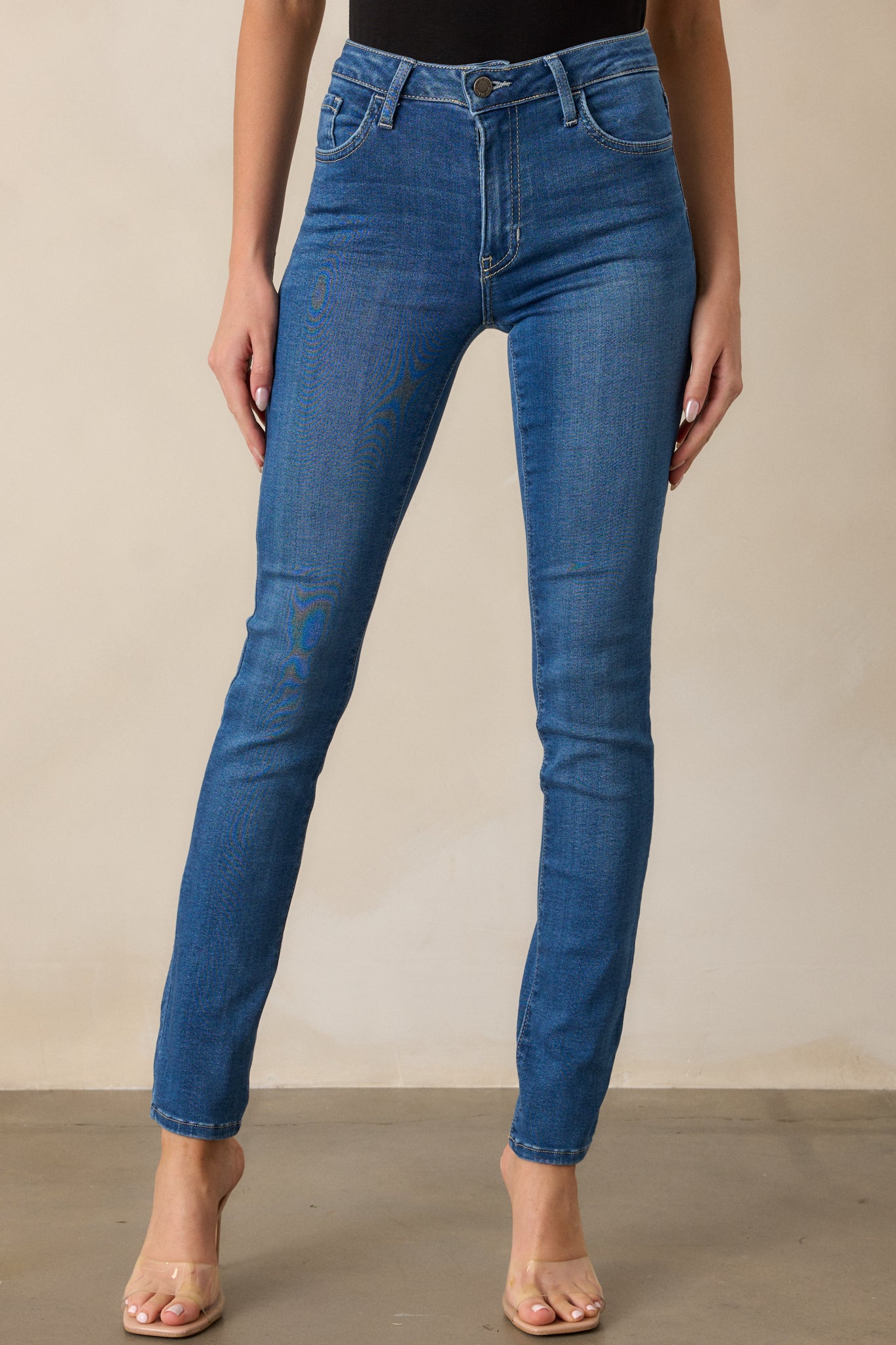 A cropped shot of the medium wash jeans, focusing on the high waist design and the functional belt loops. The smooth, clean front is highlighted, showing the sleek fit.