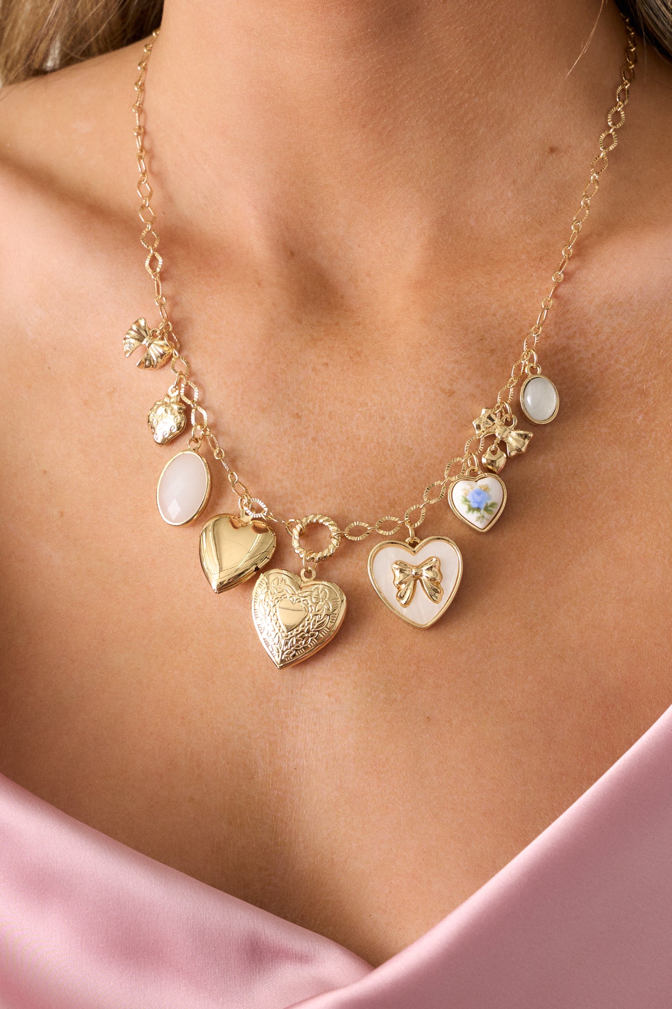 Close-up of the gold necklace focusing on the textured heart charms, and shimmering pearlescent oval charms, highlighting its delicate craftsmanship.