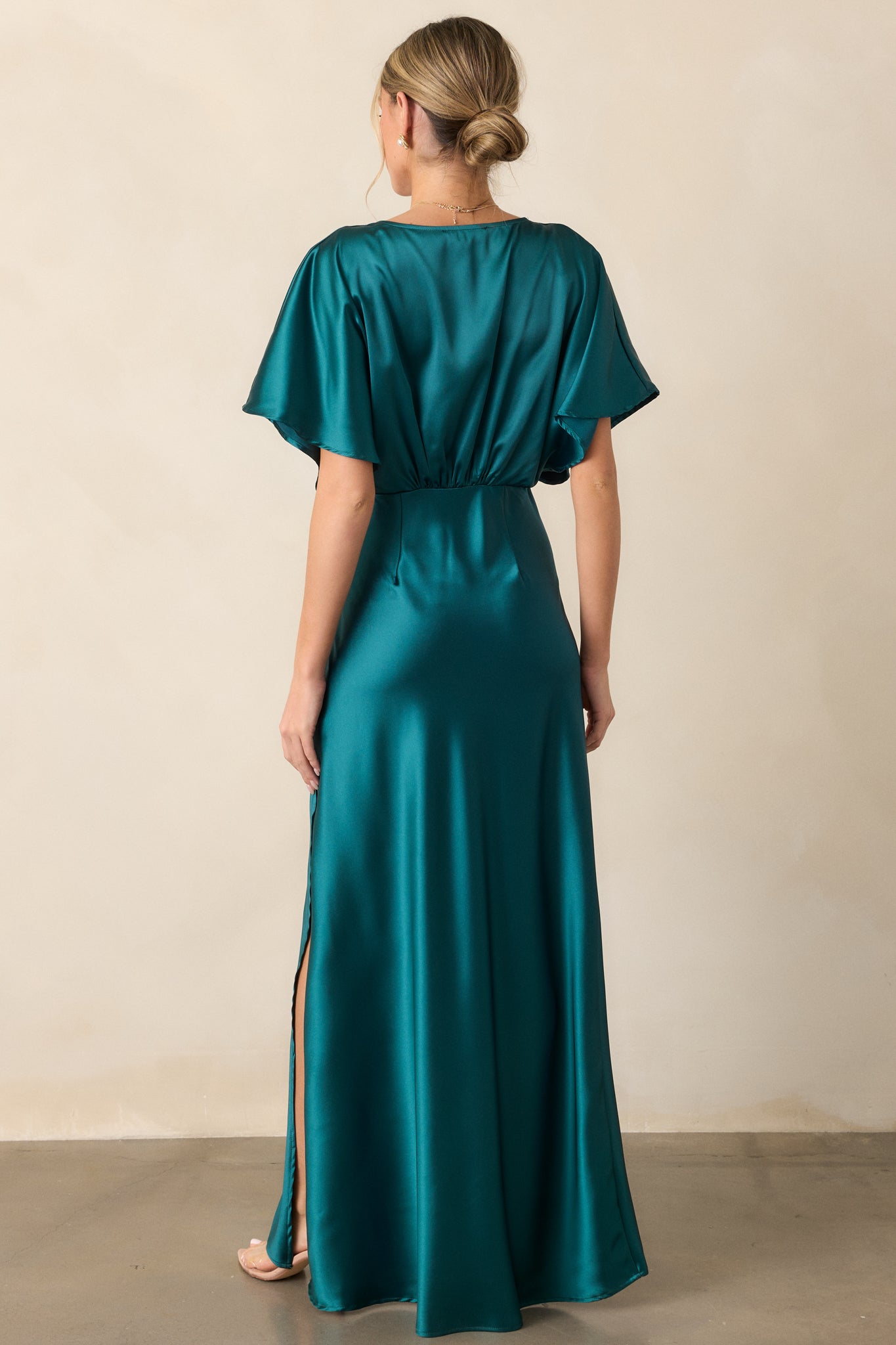 The back view of the teal dress, highlighting the kimono-style sleeves and smooth satin fabric. The deep V-neckline adds a stylish touch to the elegant design.