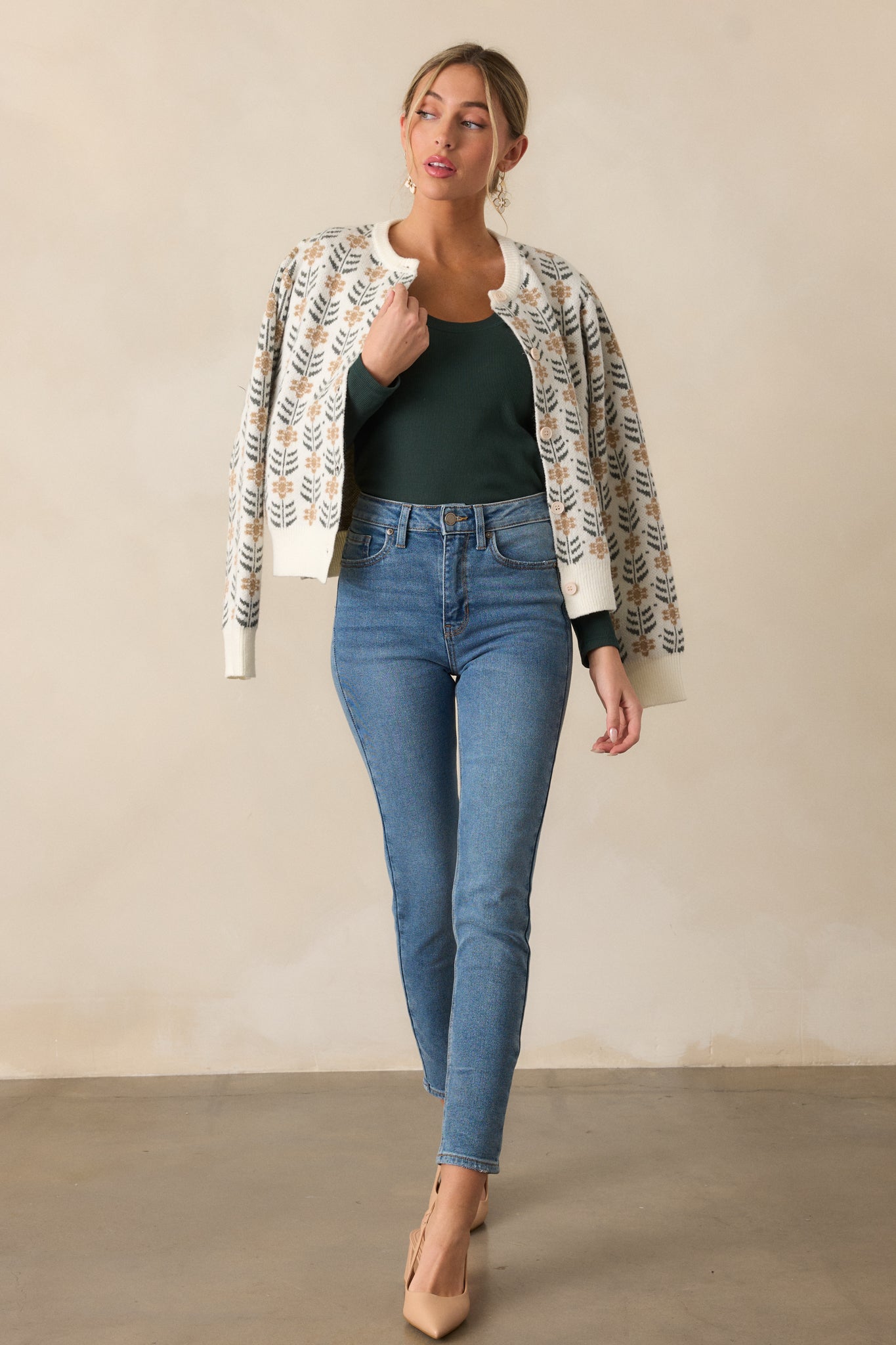 Full body view of an ivory cardigan featuring a round neckline, a repeating pattern of delicate beige floral motifs with dark green leaf accents, ribbed hems and long sleeves.