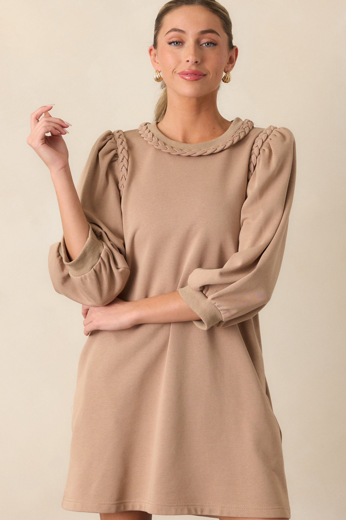 Front view of a tan dress featuring a braided neckline, braided shoulder detailing, puff 3/4 sleeves and a boxy fit.