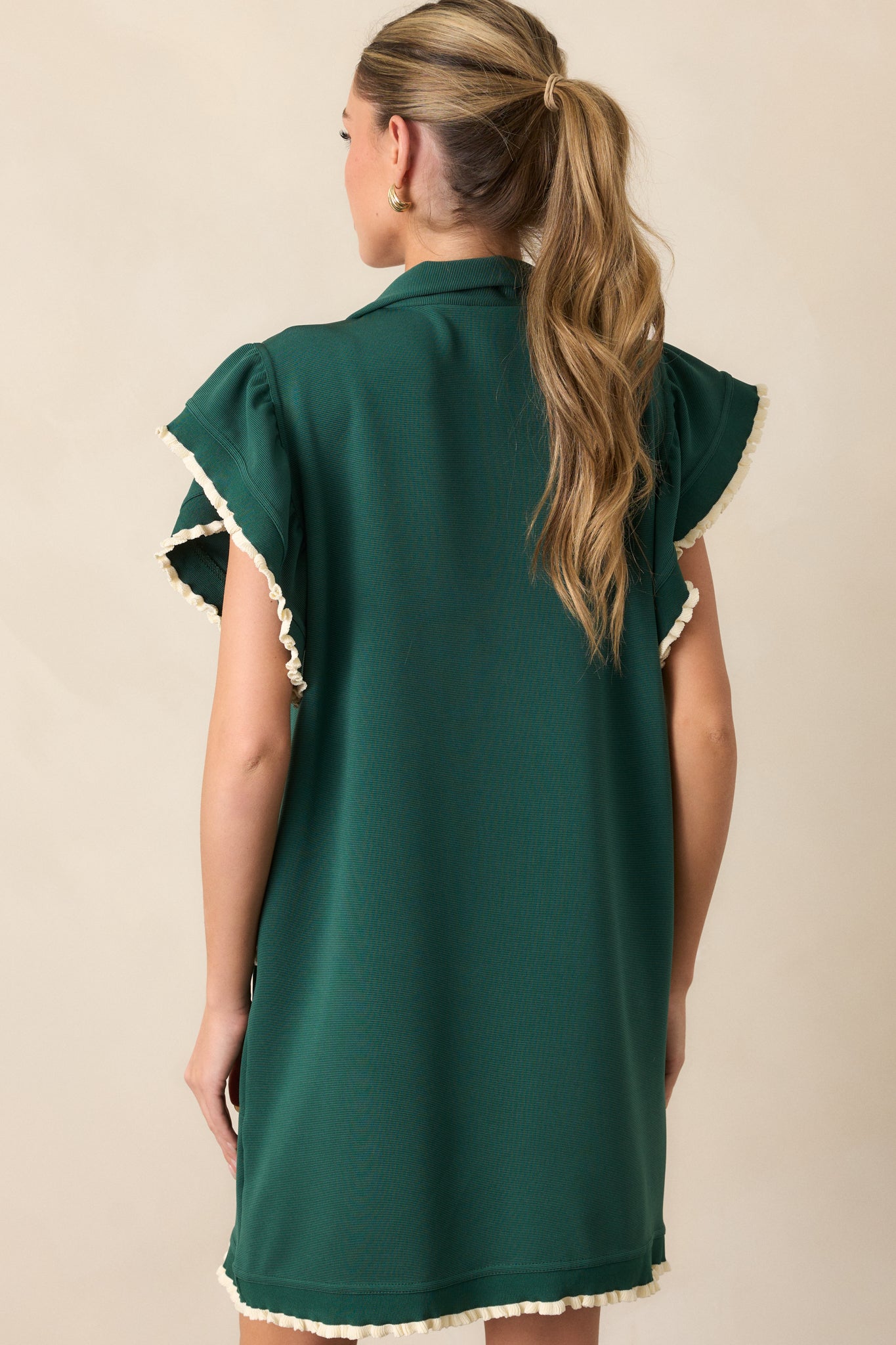 The back of the dress, showing the smooth green fabric and how the hem and sleeves extend to the back.