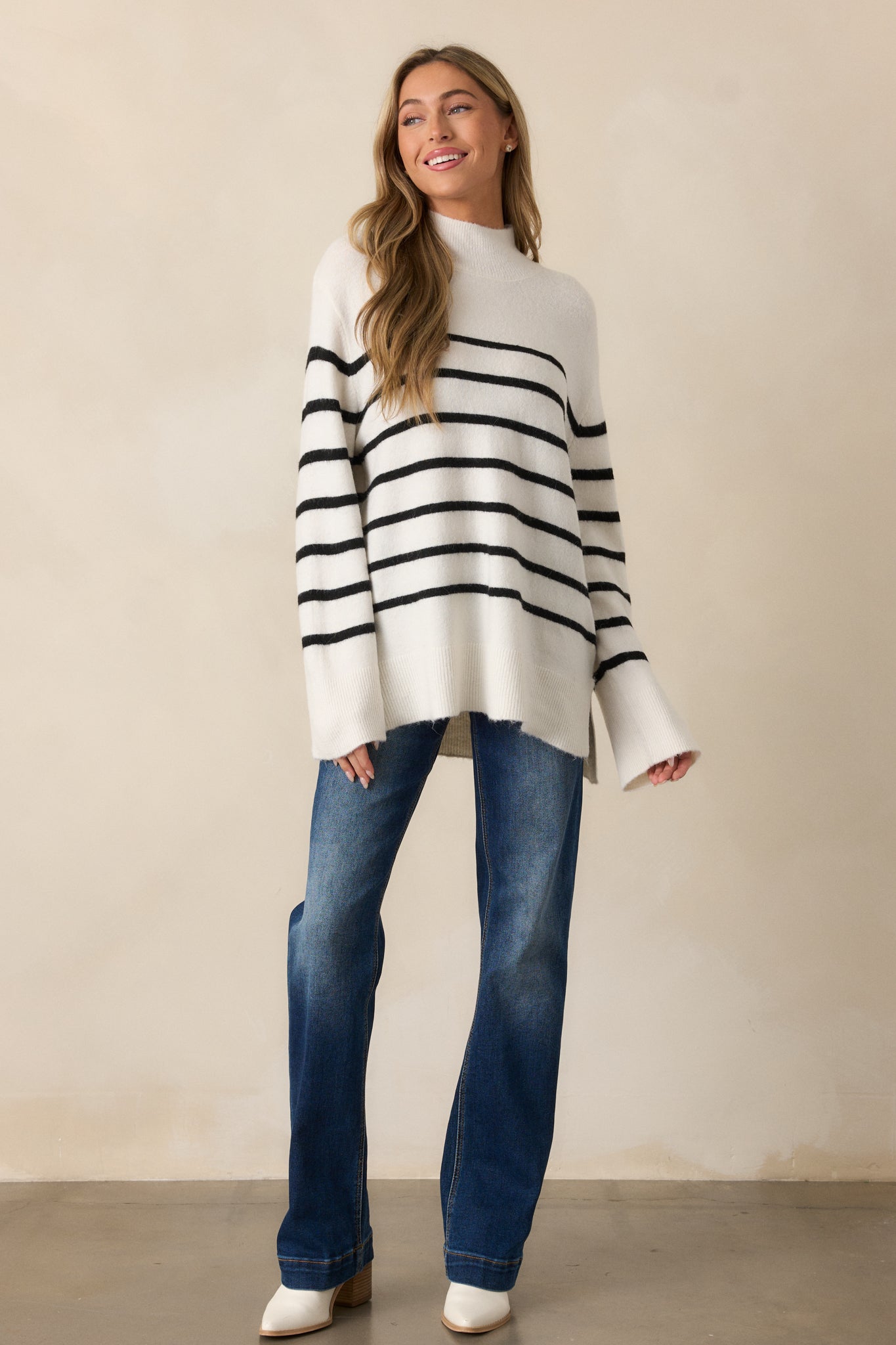 Full-body image showcasing the relaxed fit of the Sea Salt Ivory sweater, with its distinct high neck and flowing bell sleeves.