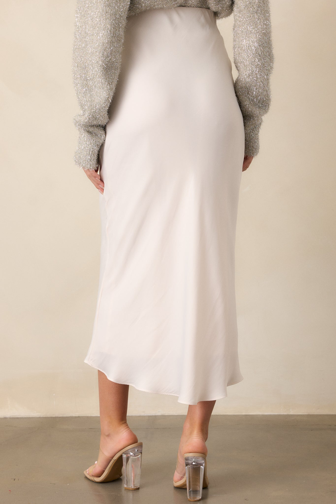 A back view of the ivory skirt, displaying its smooth satin fabric flowing to the floor, with the mid-rise elastic waistband offering a clean and simple finish.