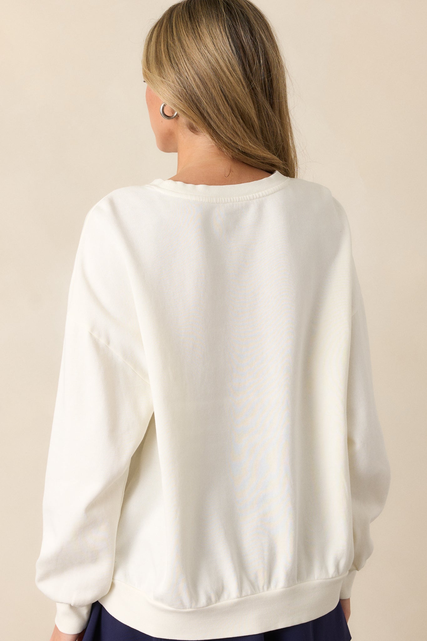 A back view of the ivory sweatshirt, showing the relaxed fit and the soft texture of the 100% cotton brushed fleece fabric.