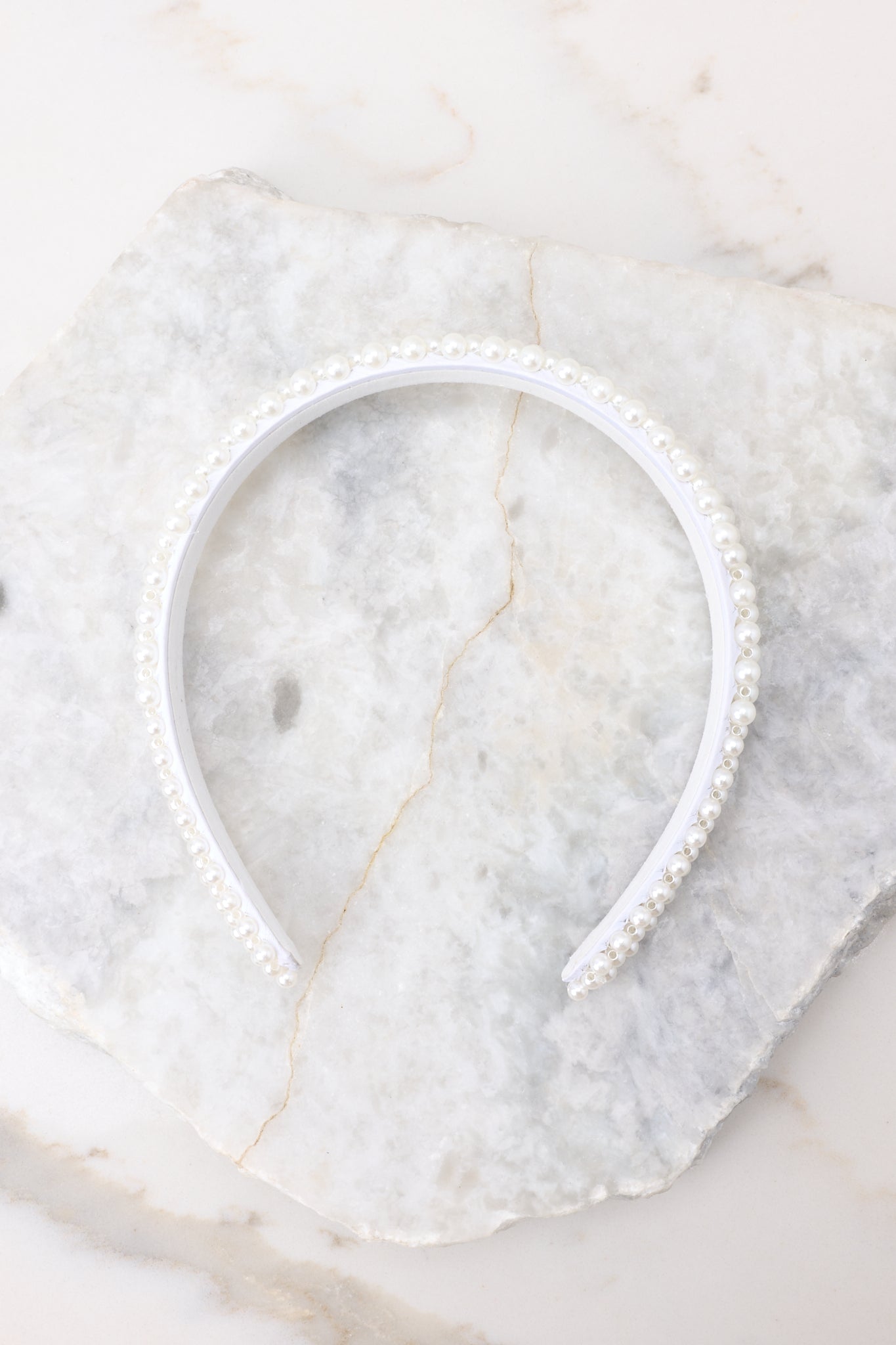 Side view of this headband that features a flexible design with pearl embellishments throughout.