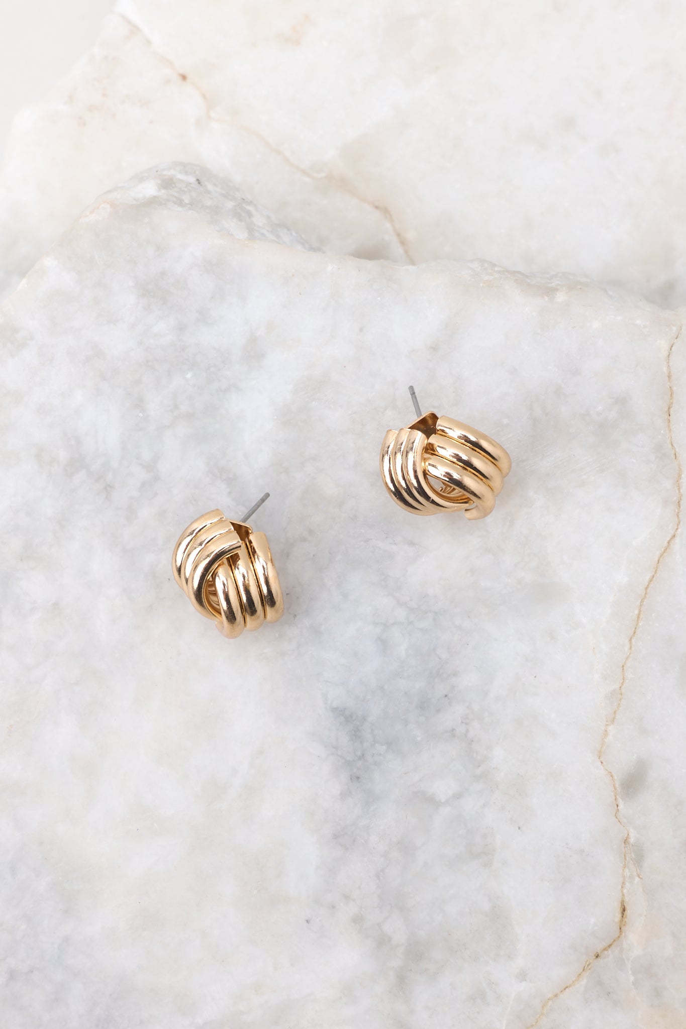 Full view of these earrings that feature a gold finish, a twisted design, and a secure post backing.