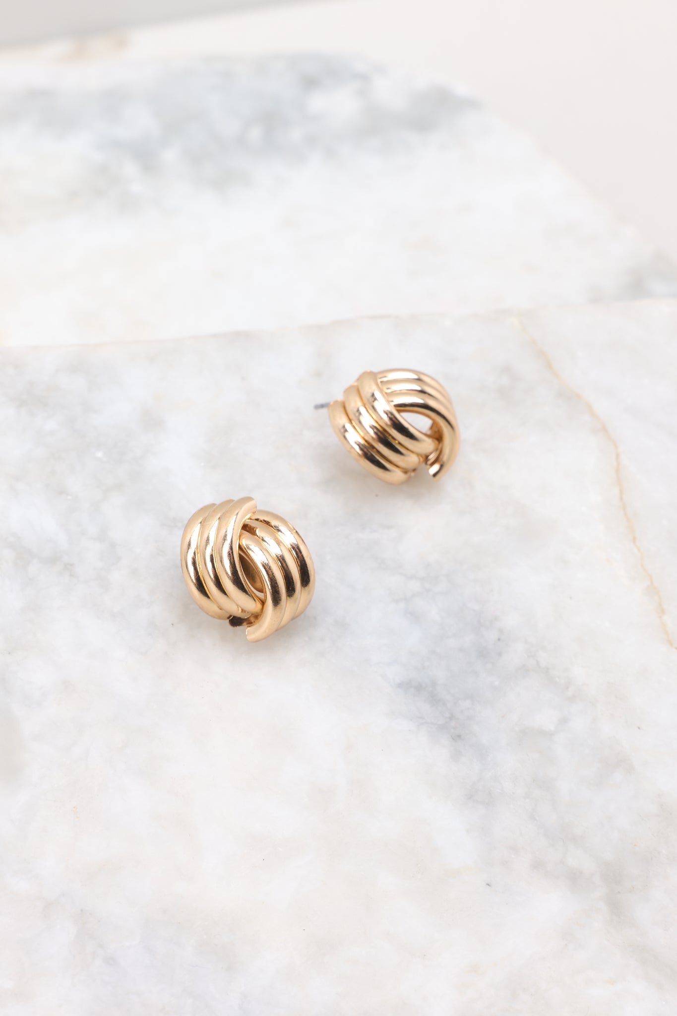 Front view of these earrings that feature a gold finish, a twisted design, and a secure post backing.