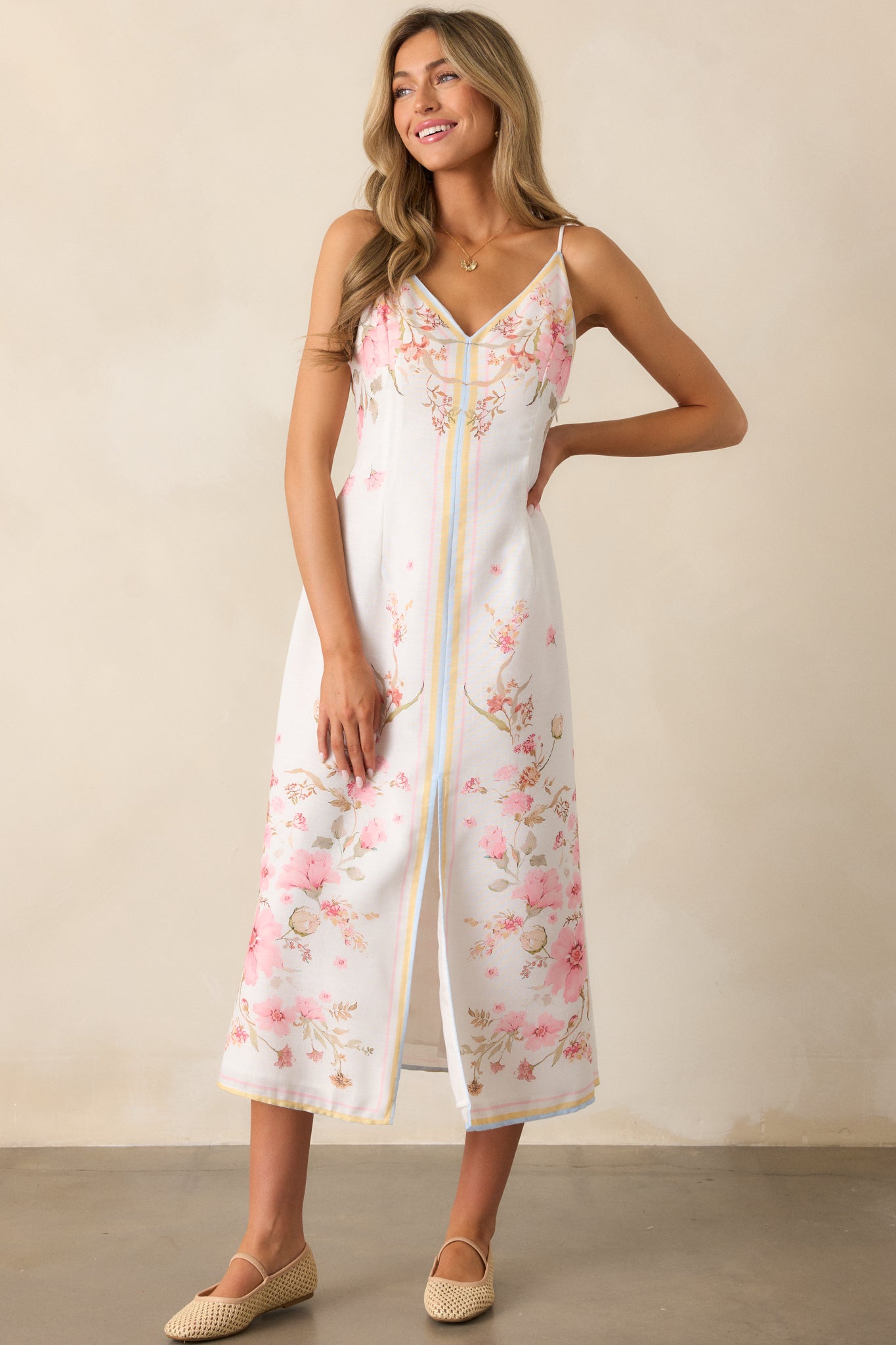 A whimsical floral midi dress flaunting a v-neckline, playful self-tie straps, and a flirtatious front slit. Its delicate flower print blooms with charm.