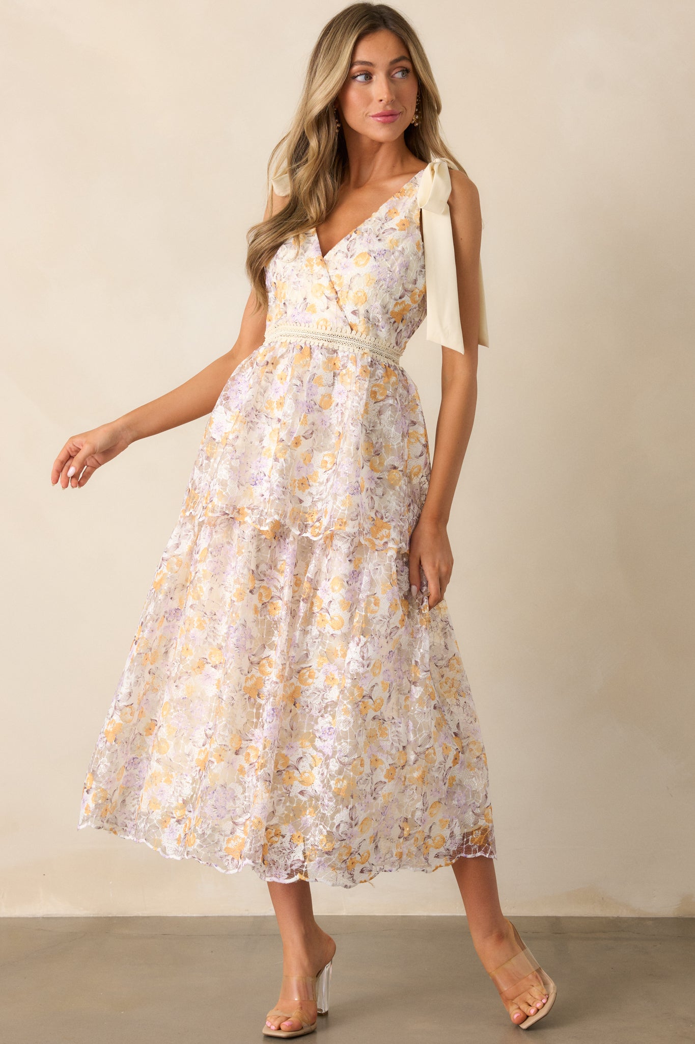 An apricot midi dress showcasing its embroidered waistband, detailed floral design, and a back zipper for a tailored fit.