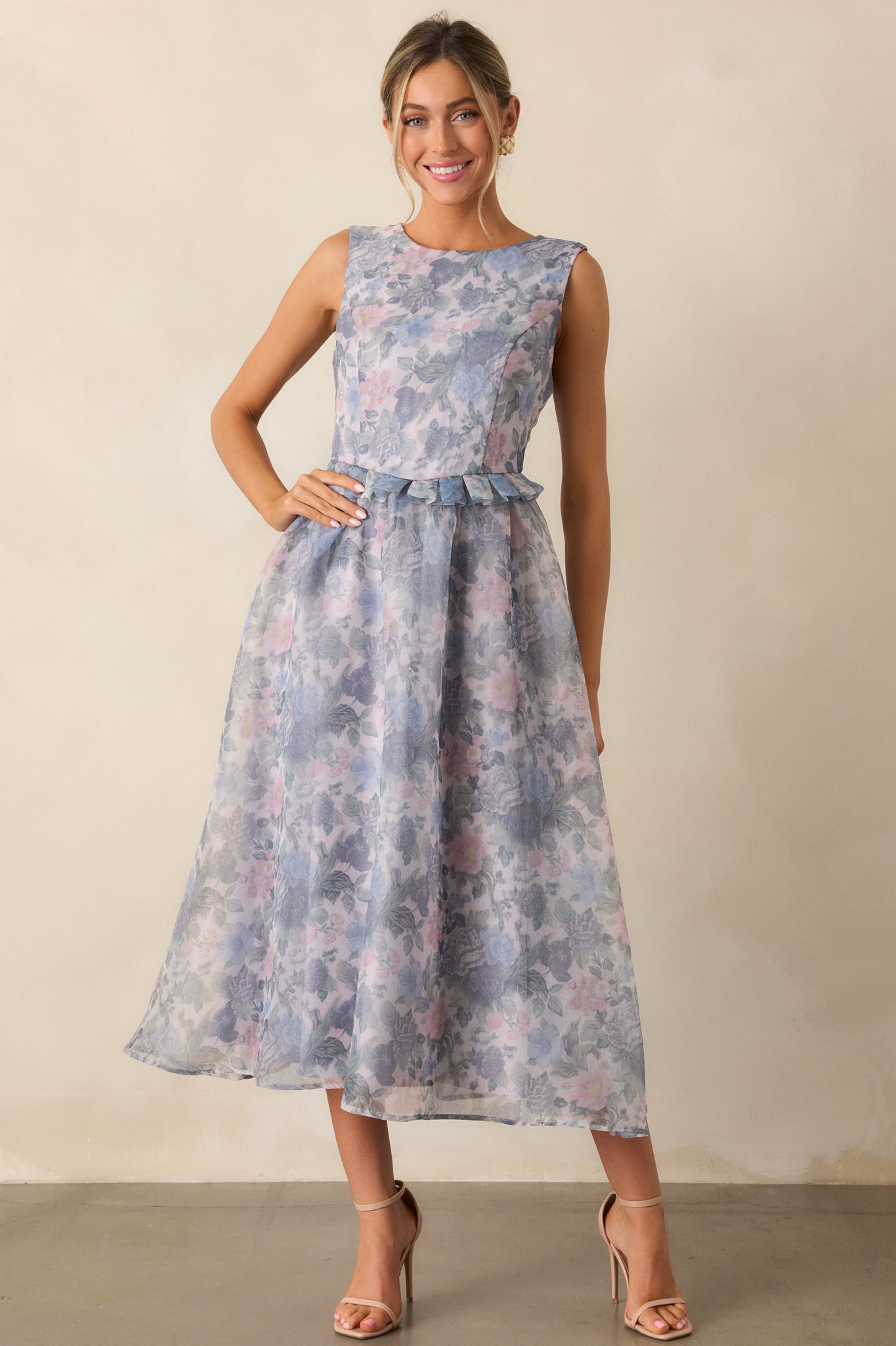 A full-length view of the ash blue dress, showcasing the rounded neckline, floral design, ruffle peplum waistband, and relaxed midi skirt that gently flows to the ankles.