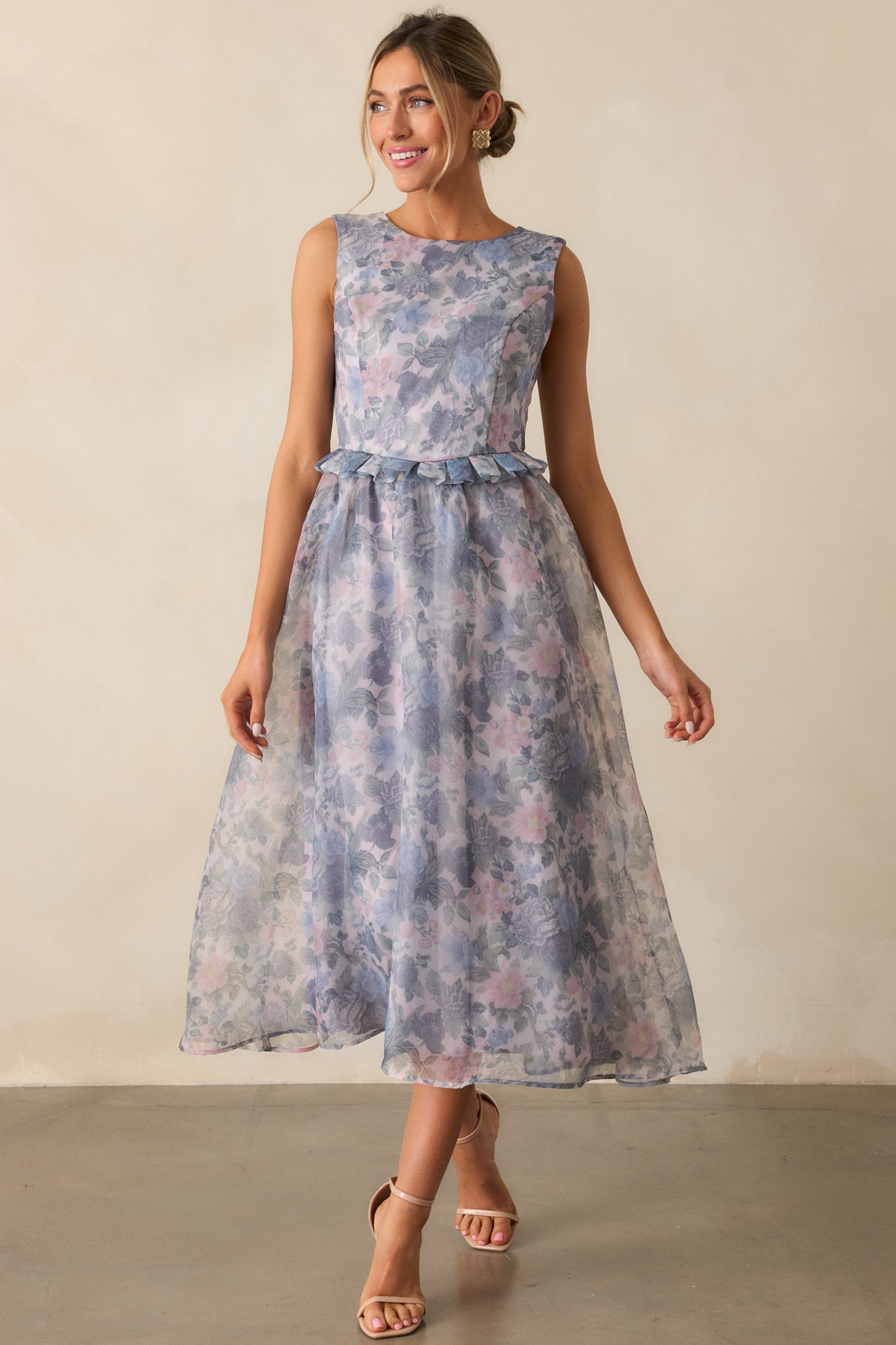 A front-facing shot highlighting the ash blue color of the dress, with a focus on the delicate floral pattern, rounded neckline, and peplum waistband leading to the relaxed, flowing midi skirt.