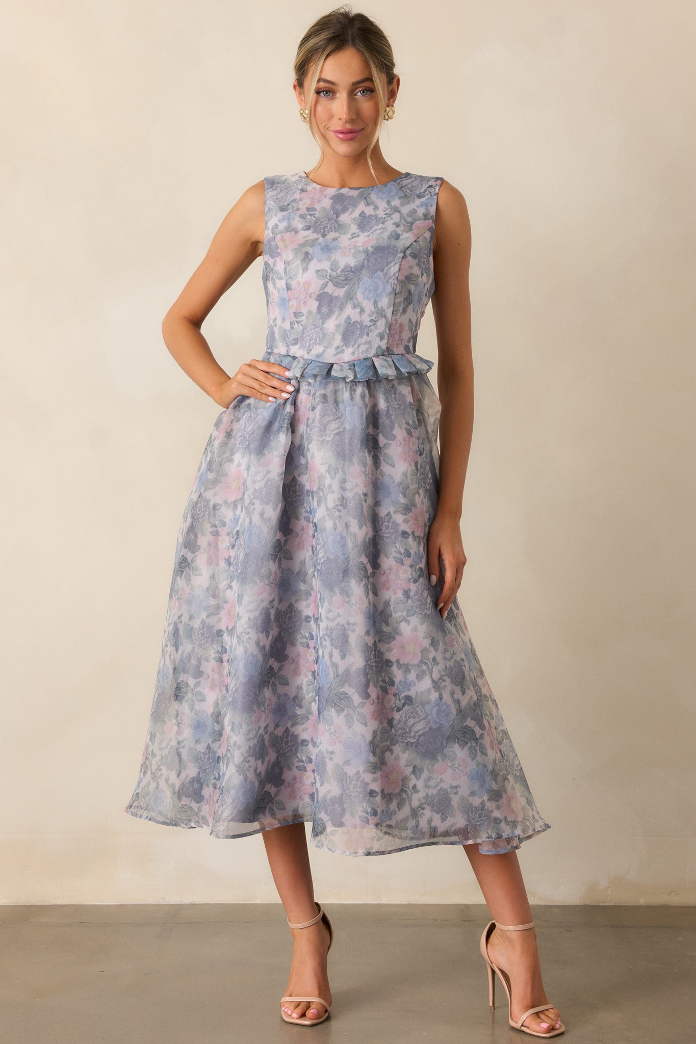 A front view of the dress, showcasing the rounded neckline, discrete zipper at the back, floral pattern, and the peplum waistband accentuating the waist, flowing into the relaxed midi skirt.