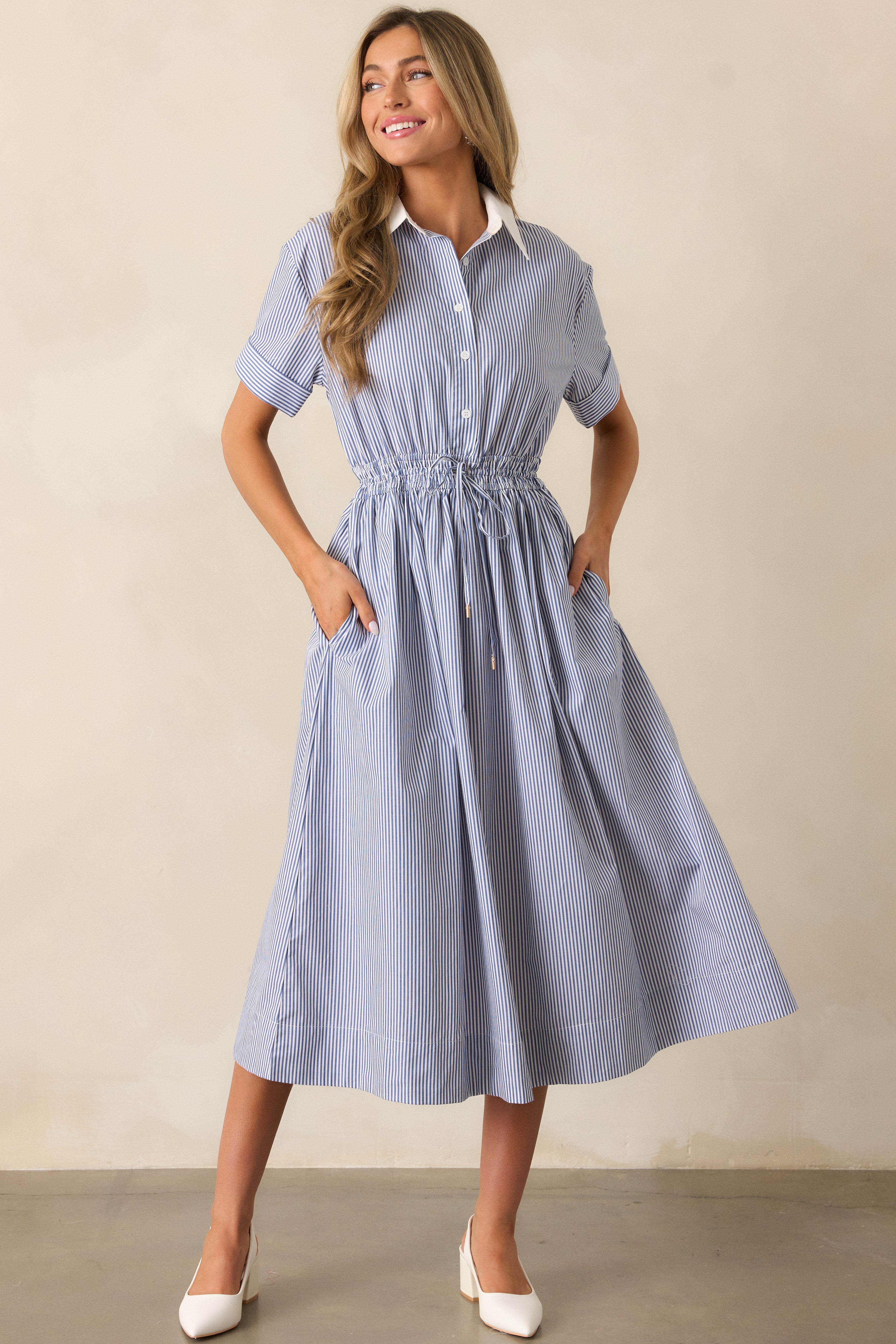 Angled view of the blue dress showcasing the fitted bodice, cuffed short sleeves, and the clean lines of the dress’s silhouette.