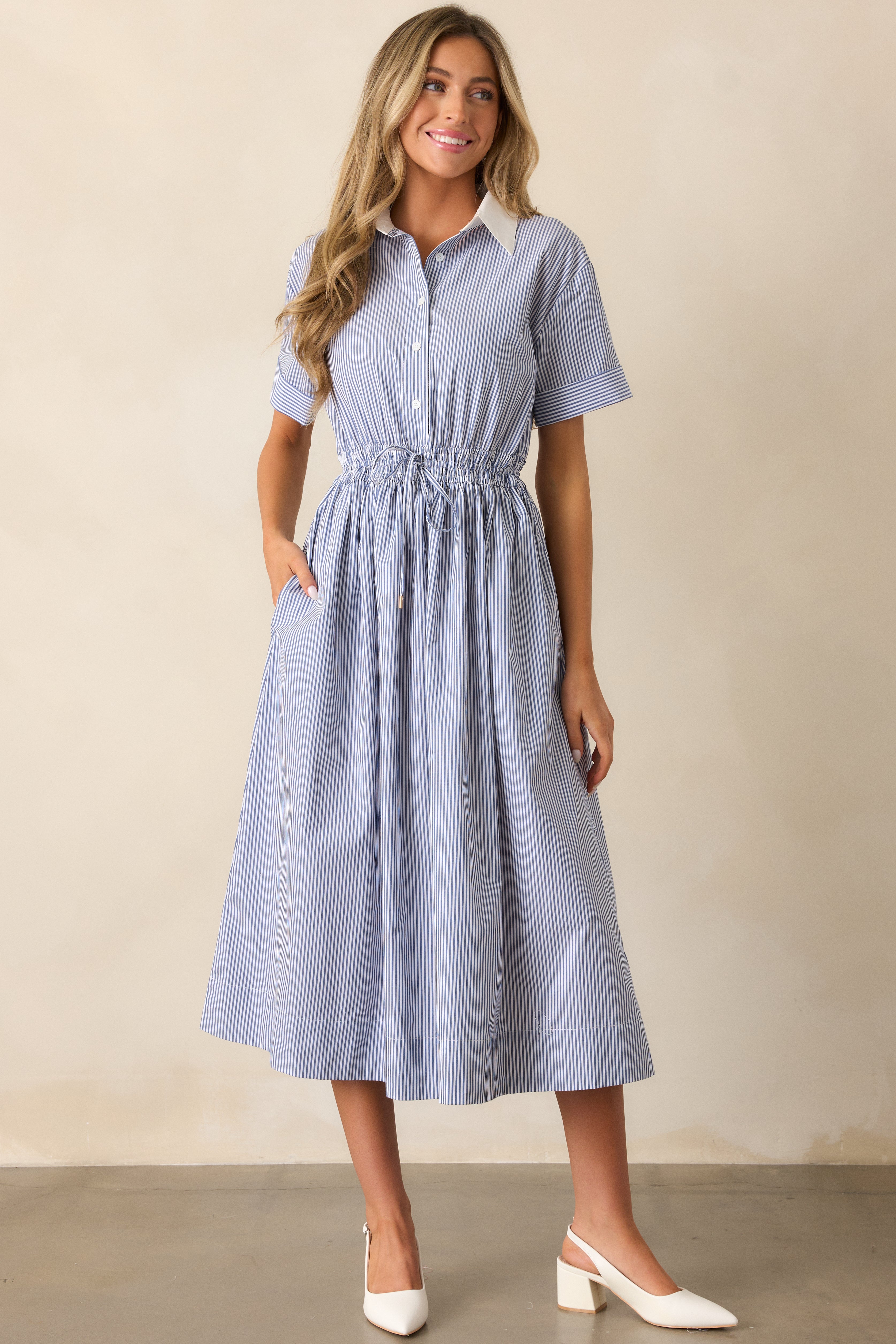 Front-facing full shot of the blue dress highlighting the white collared neckline, functional pockets, and short cuffed sleeves.