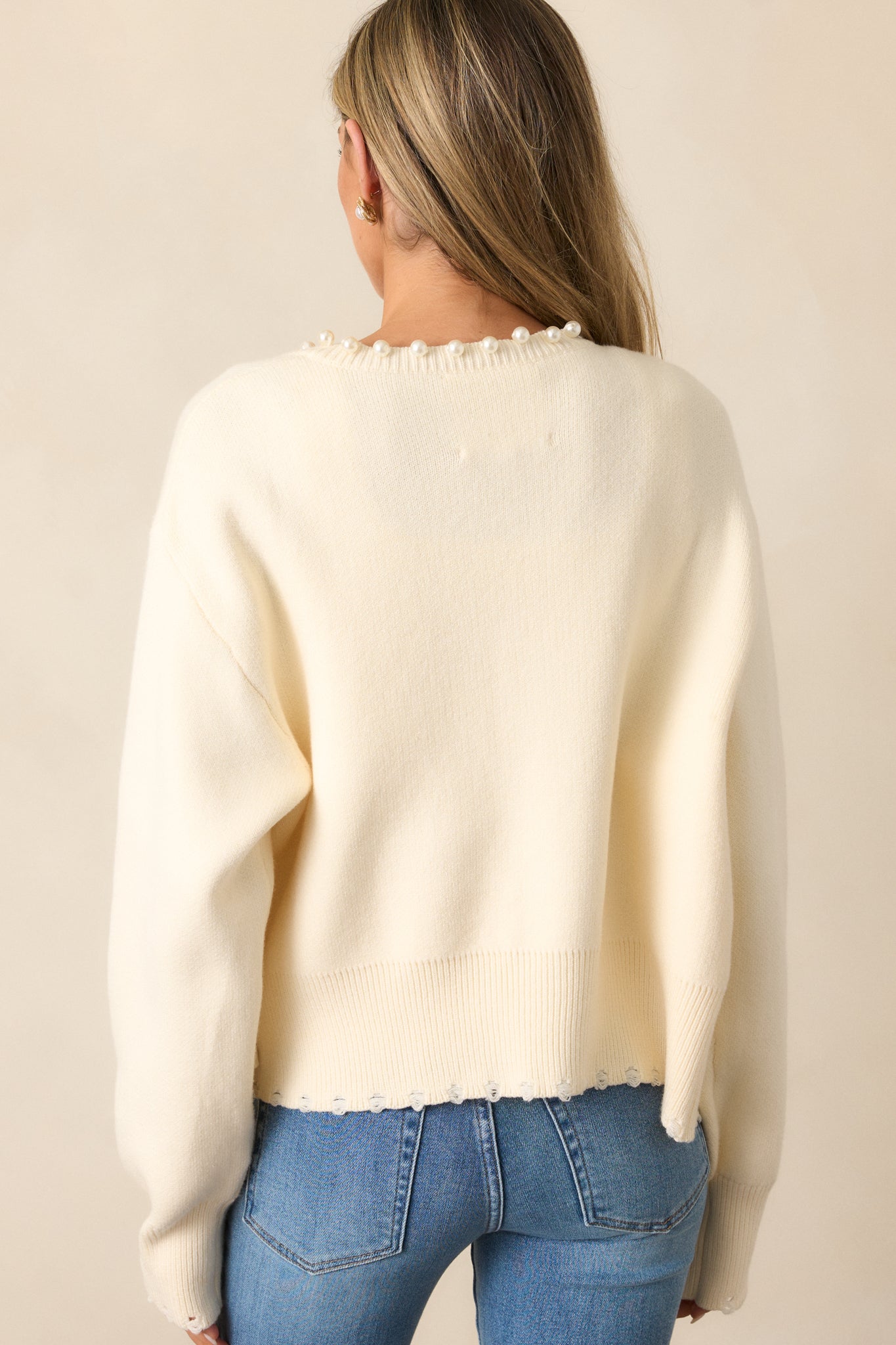 The back of the ivory cardigan emphasizes its simple, clean design and seamless elegance.