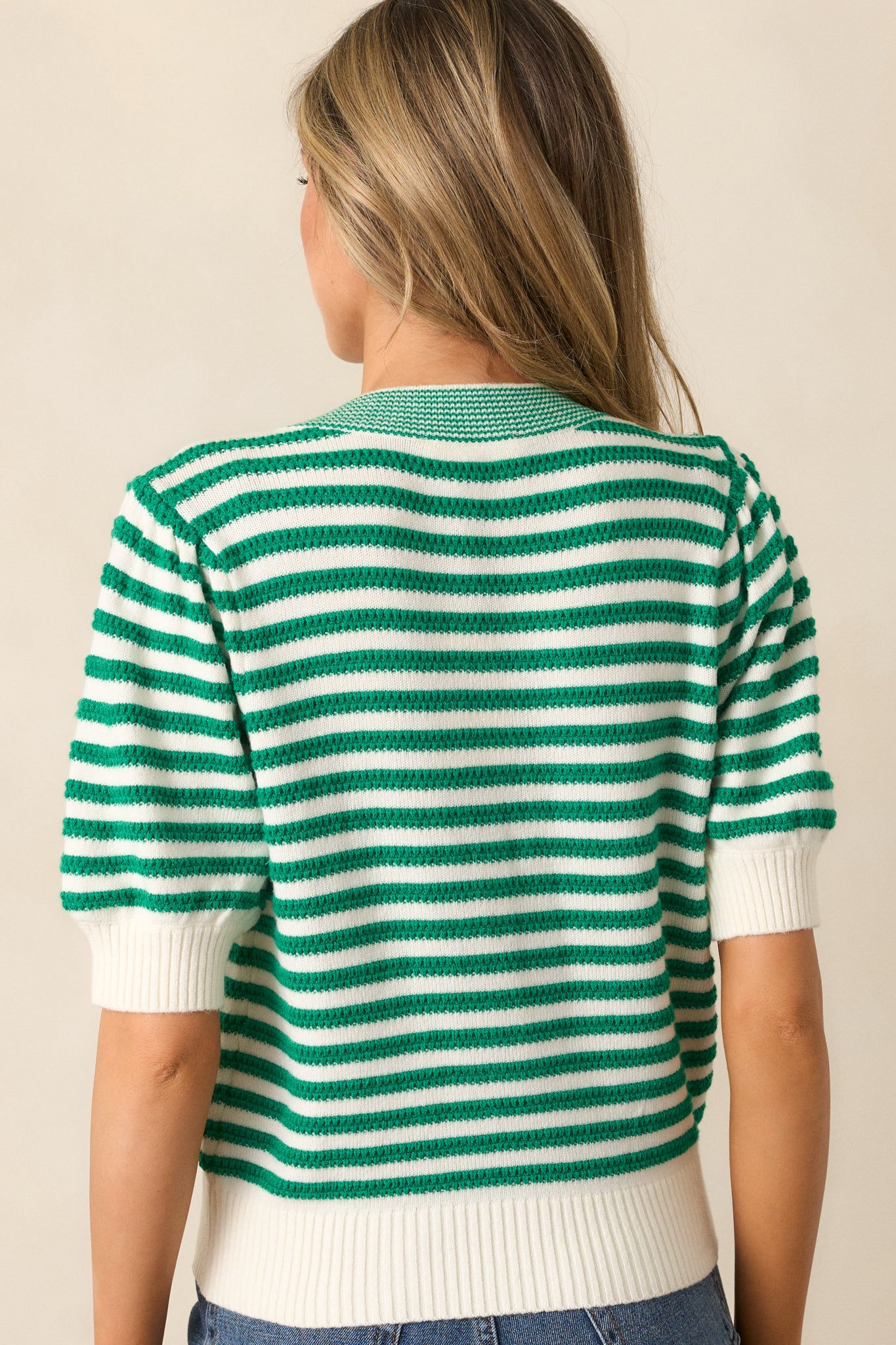 The back of the green top, displaying the continuation of the striped print and puff sleeve design with ribbed cuffs.